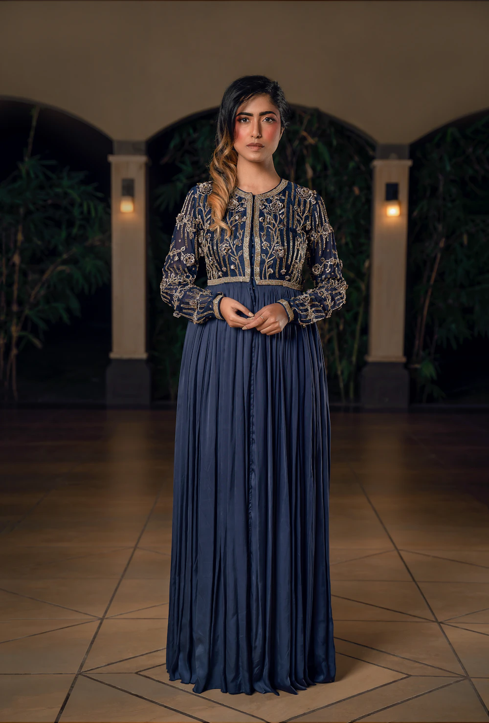 Woman in a long blue dress with ornate embroidered sleeves