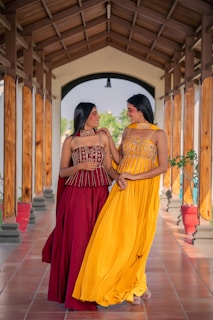Two women in ethnic wear posing together outdoors.
