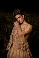 A woman in a golden dress with ornate sleeves.