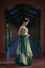 Woman in a green embroidered lehenga outfit poses elegantly.