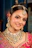 A smiling woman adorned in traditional indian jewelry and attire.