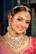 A smiling woman adorned in traditional indian jewelry and attire.