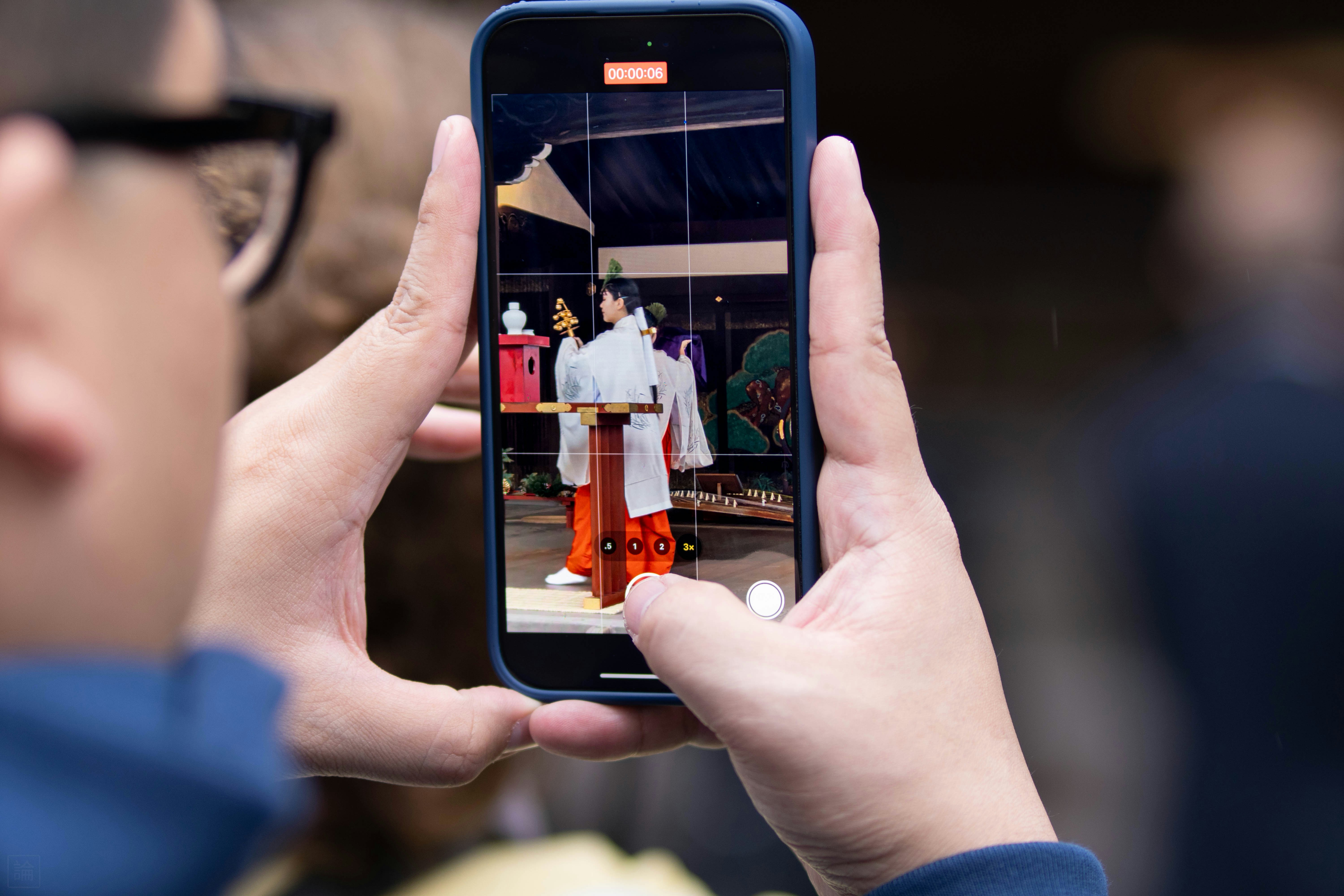 Person filming a traditional japanese wedding couple on phone.