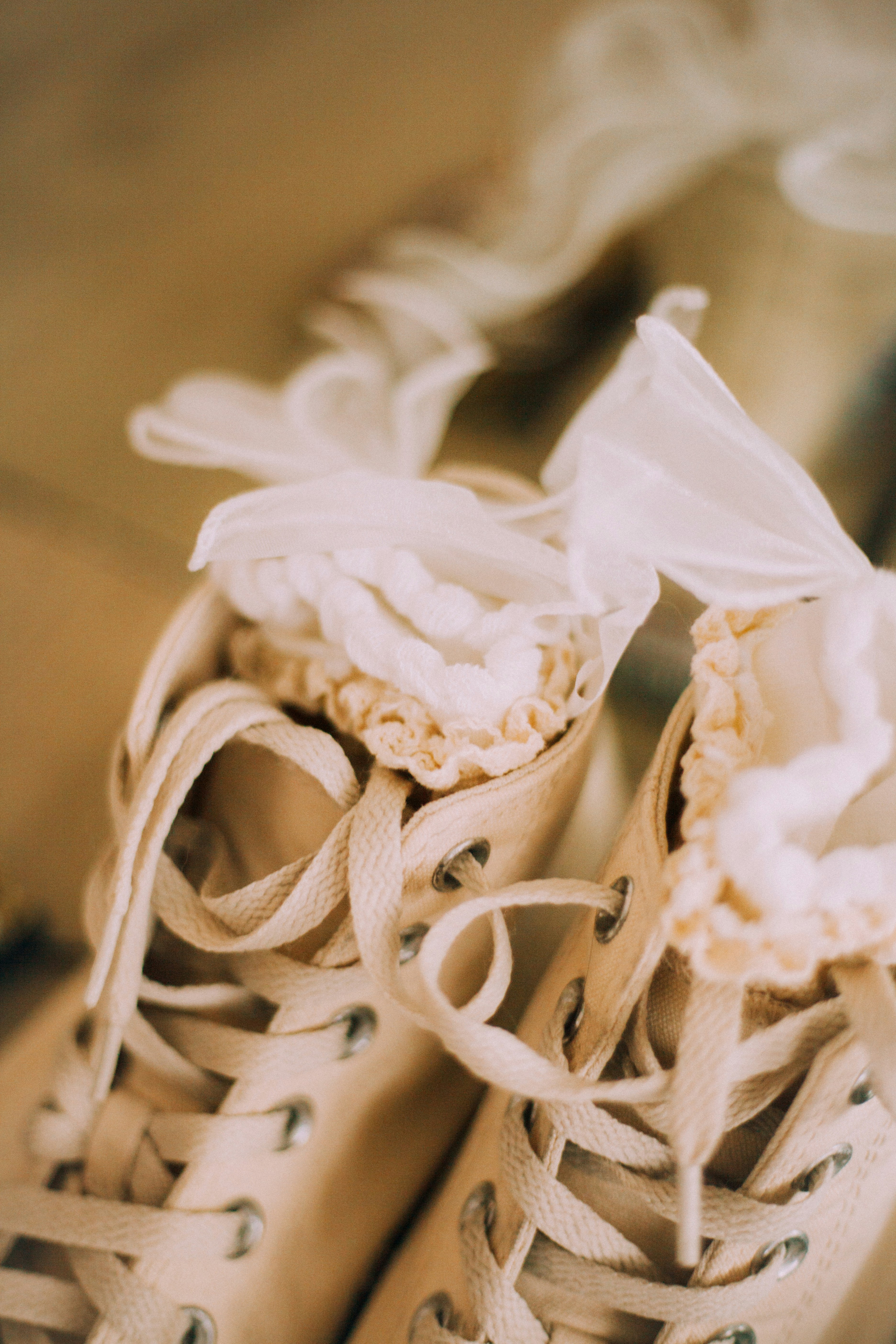 Close-up of white lace-trimmed sneakers with tied laces.