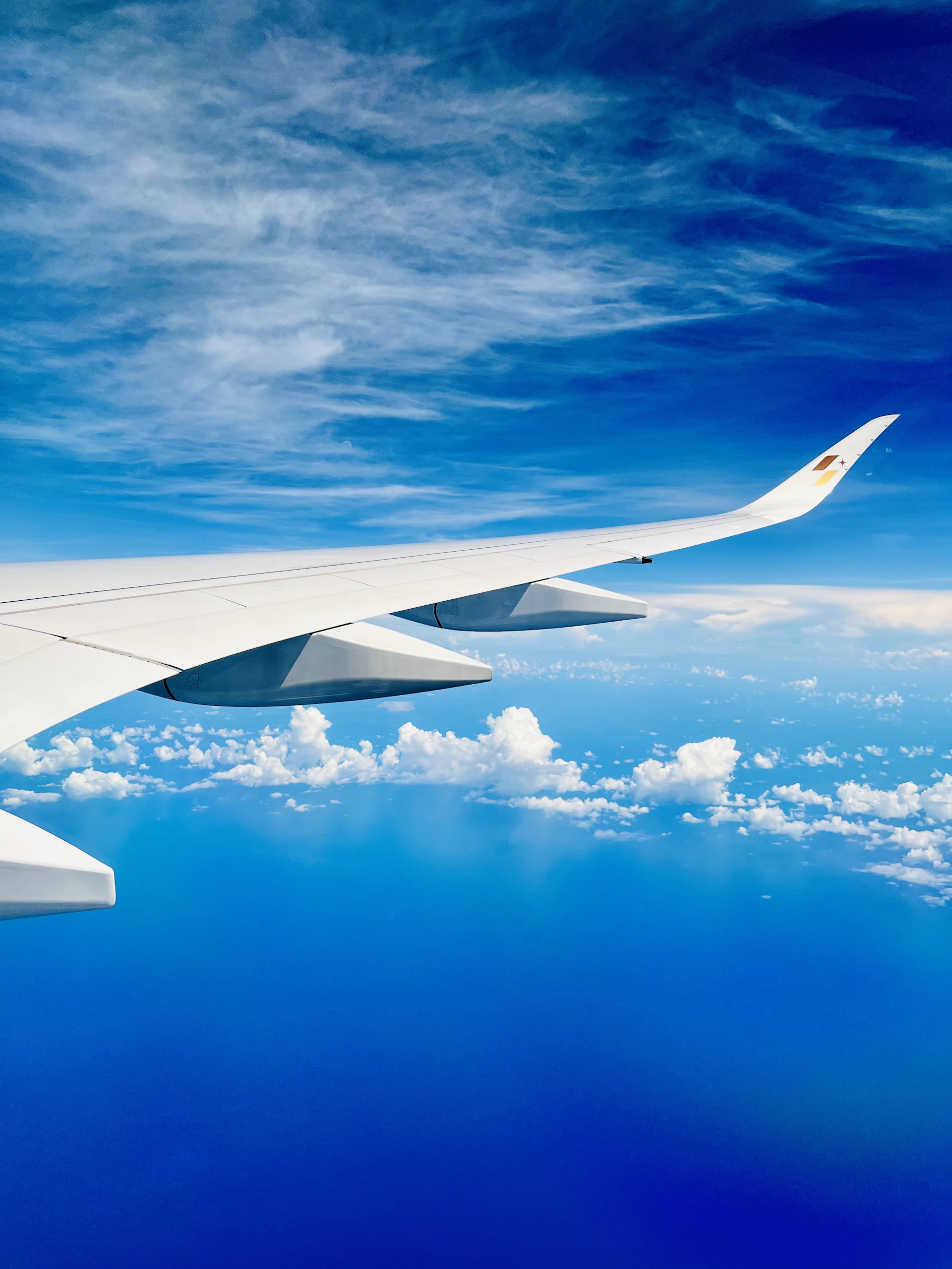 Airplane wing soaring above clouds and ocean