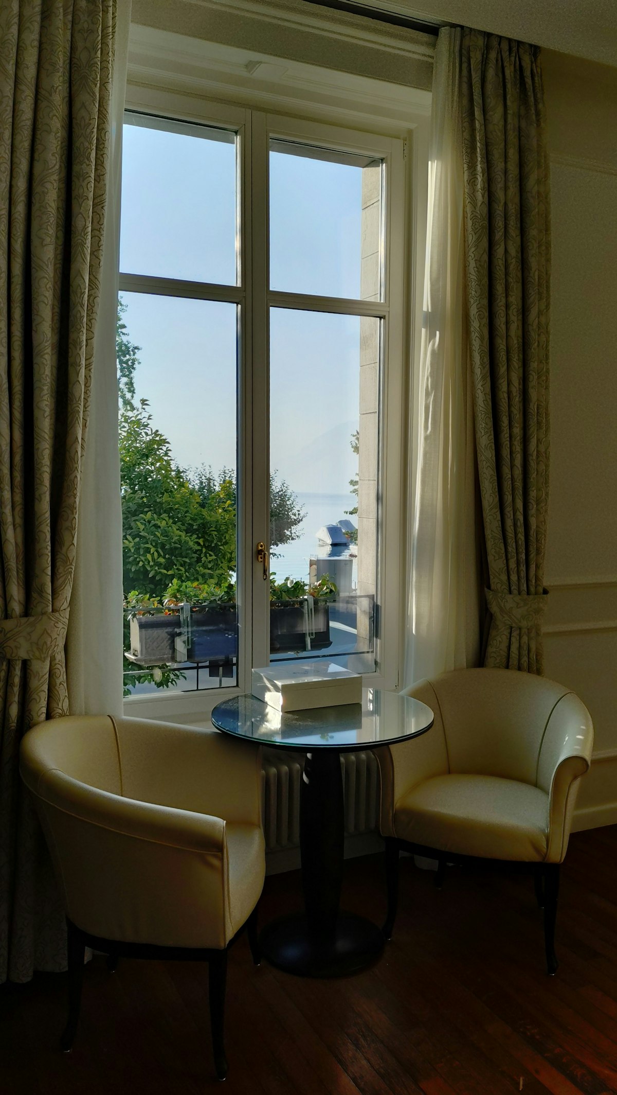 Elegant hotel room with two armchairs by a window overlooking a lake