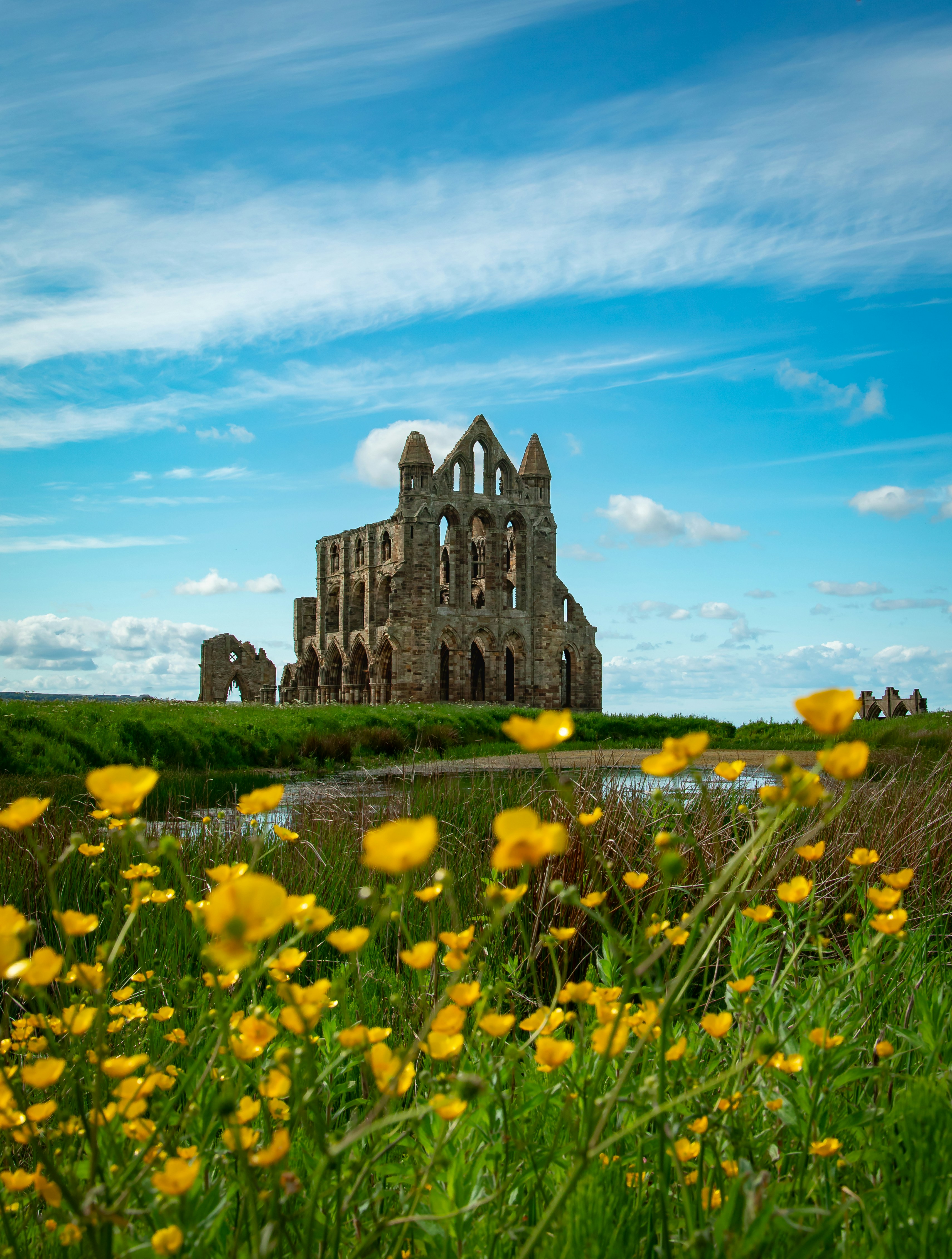 Historic abbey ruins stand against a blue sky with clouds.