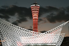 Kobe port tower illuminated red against twilight sky.