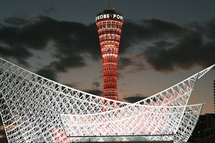 Kobe port tower illuminated red against twilight sky.