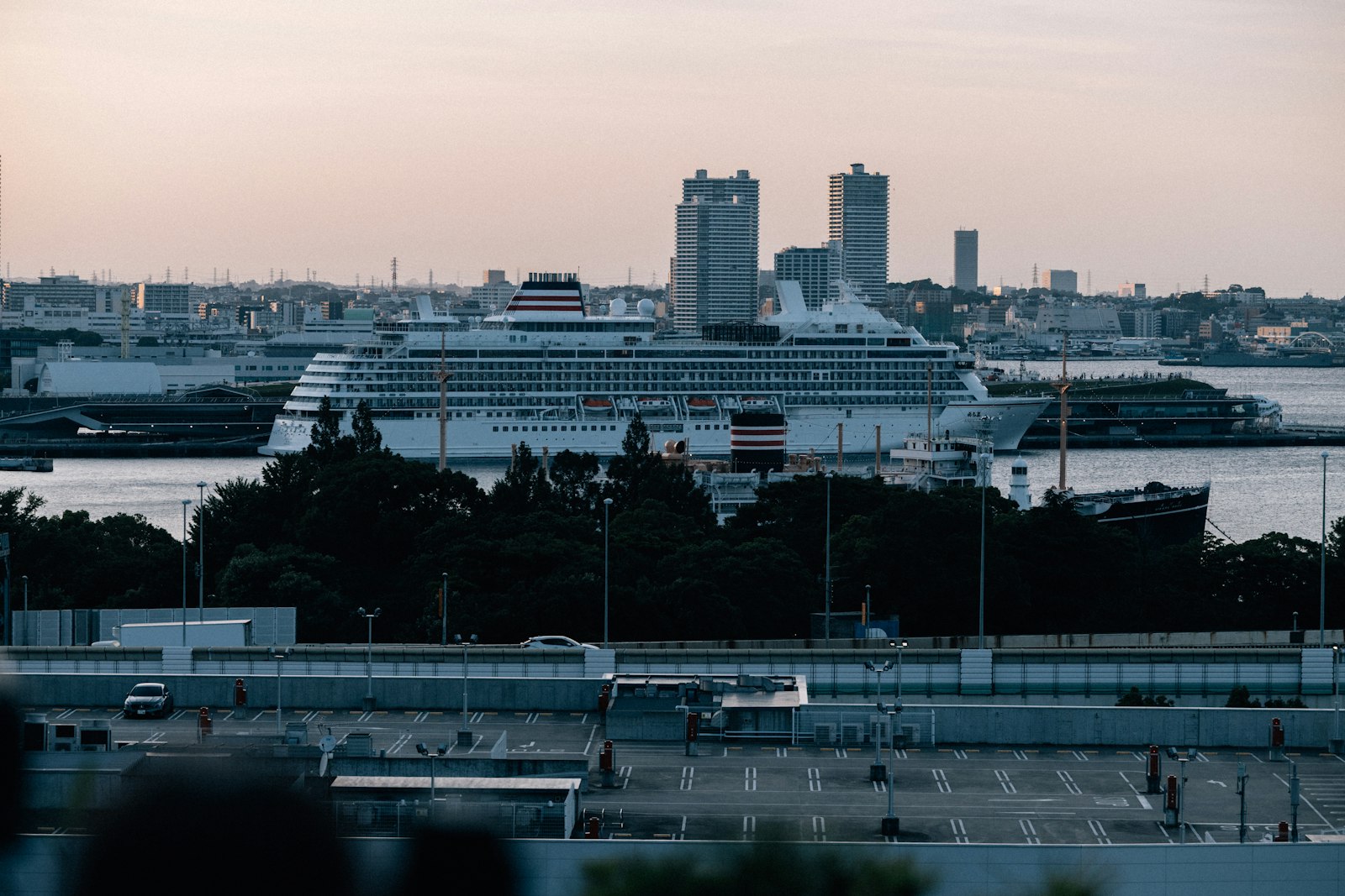 Cruise ship docked in Yokohama harbor at dusk with the city skyline behind