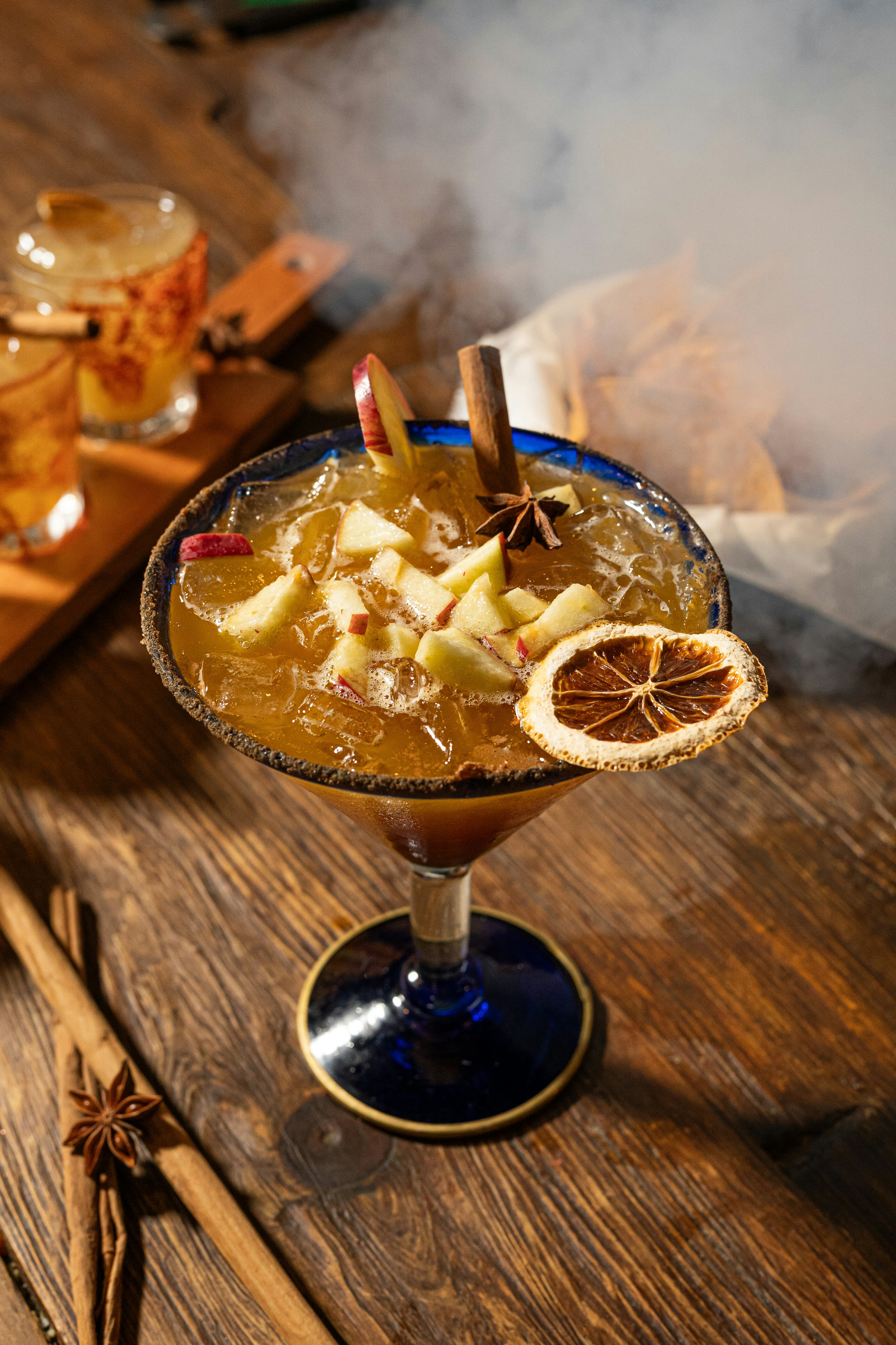 A festive cocktail garnished with apple slices and cinnamon.
