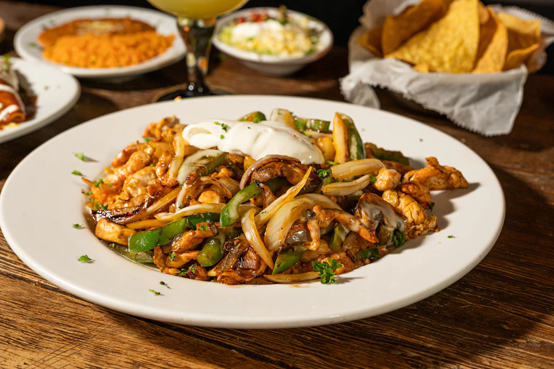 A skillet of warm Tex-Mex food served with colorful toppings and a rustic table setting.