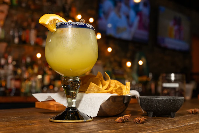 A bright margarita with a salted rim and lime, served with chips at the bar