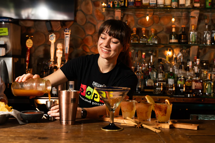 A bartender pouring a craft cocktail at a bright bar