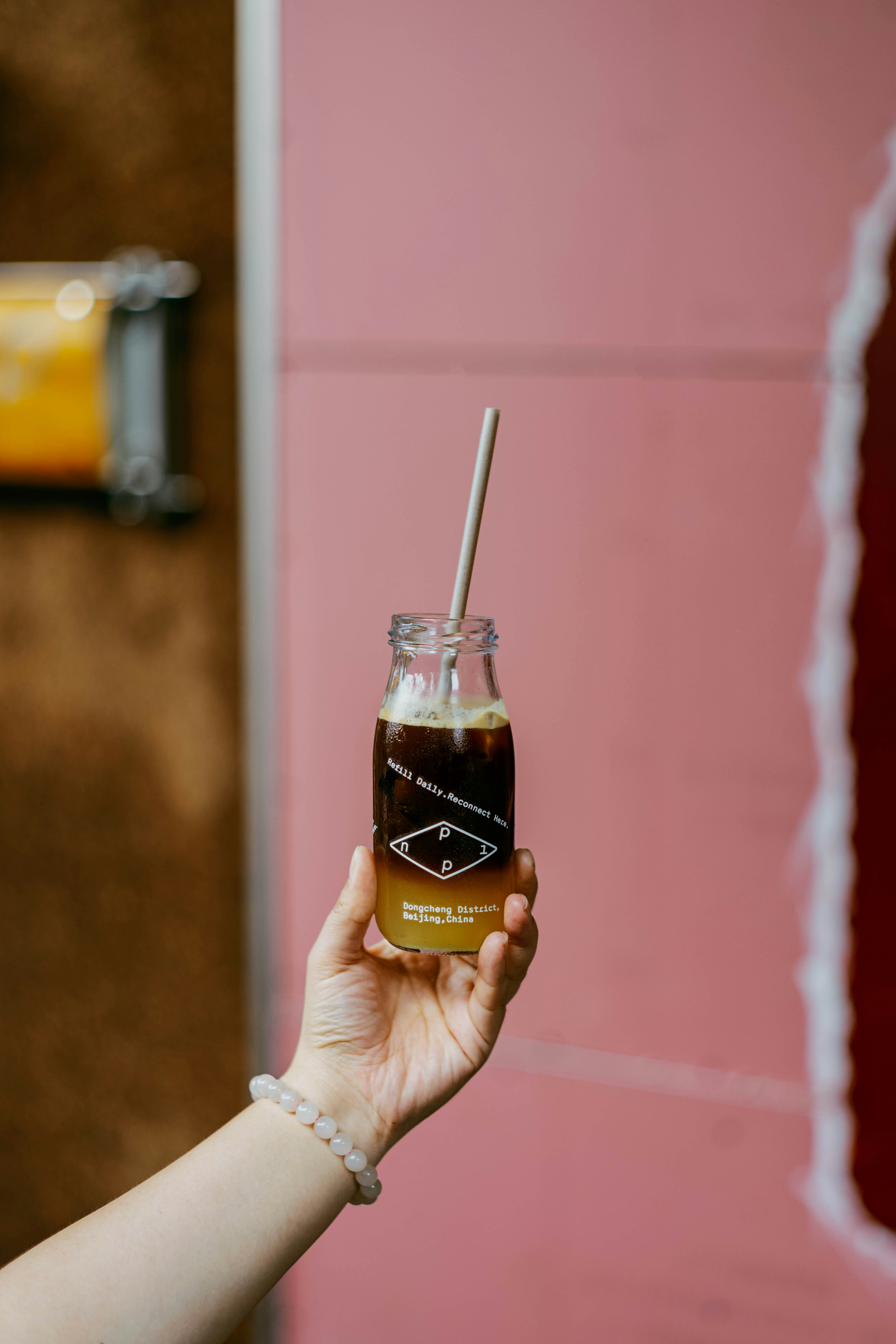 Mão segurando uma bebida de café engarrafada com canudo.