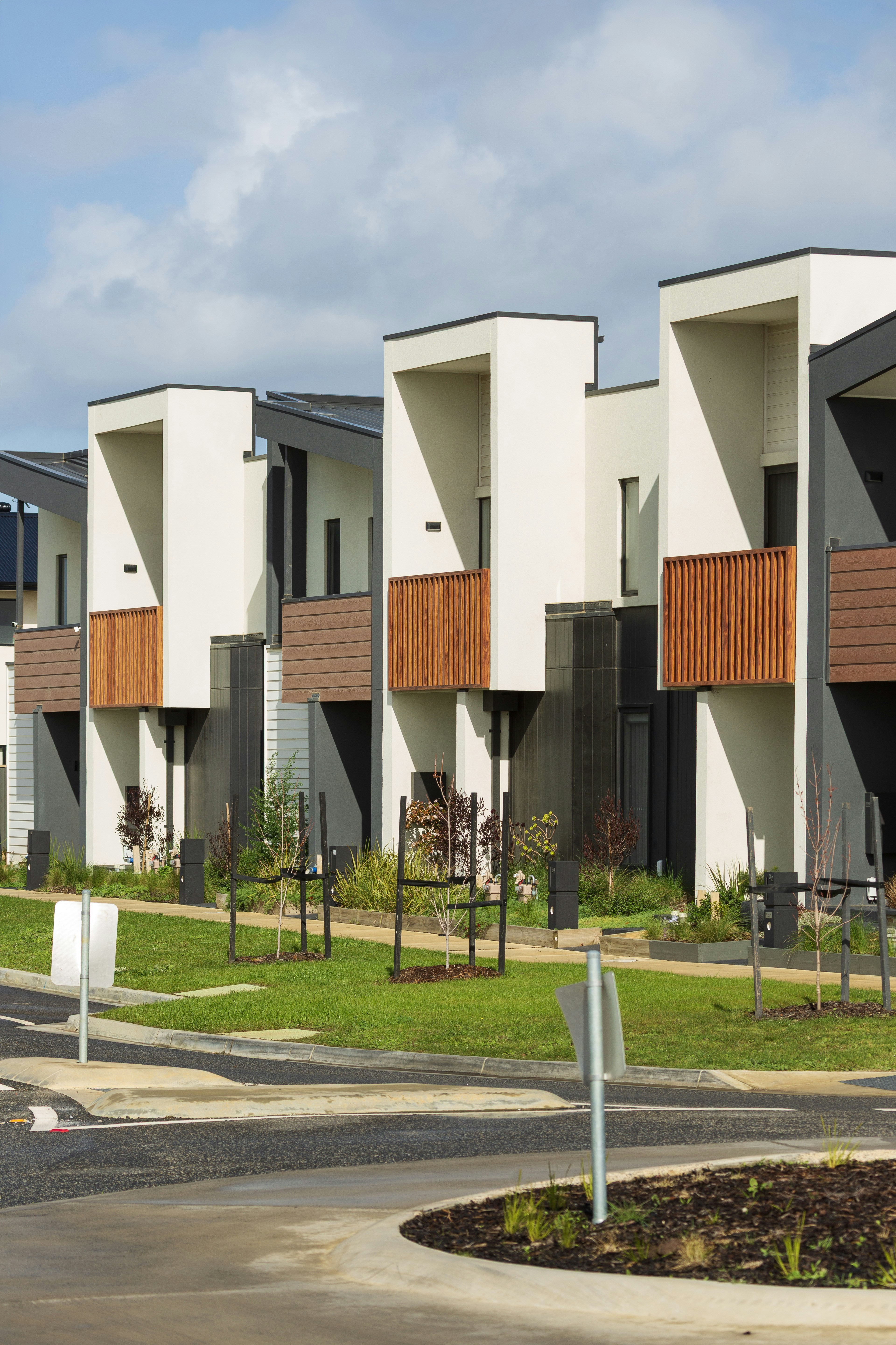 Modern townhouses with wooden balconies under a cloudy sky