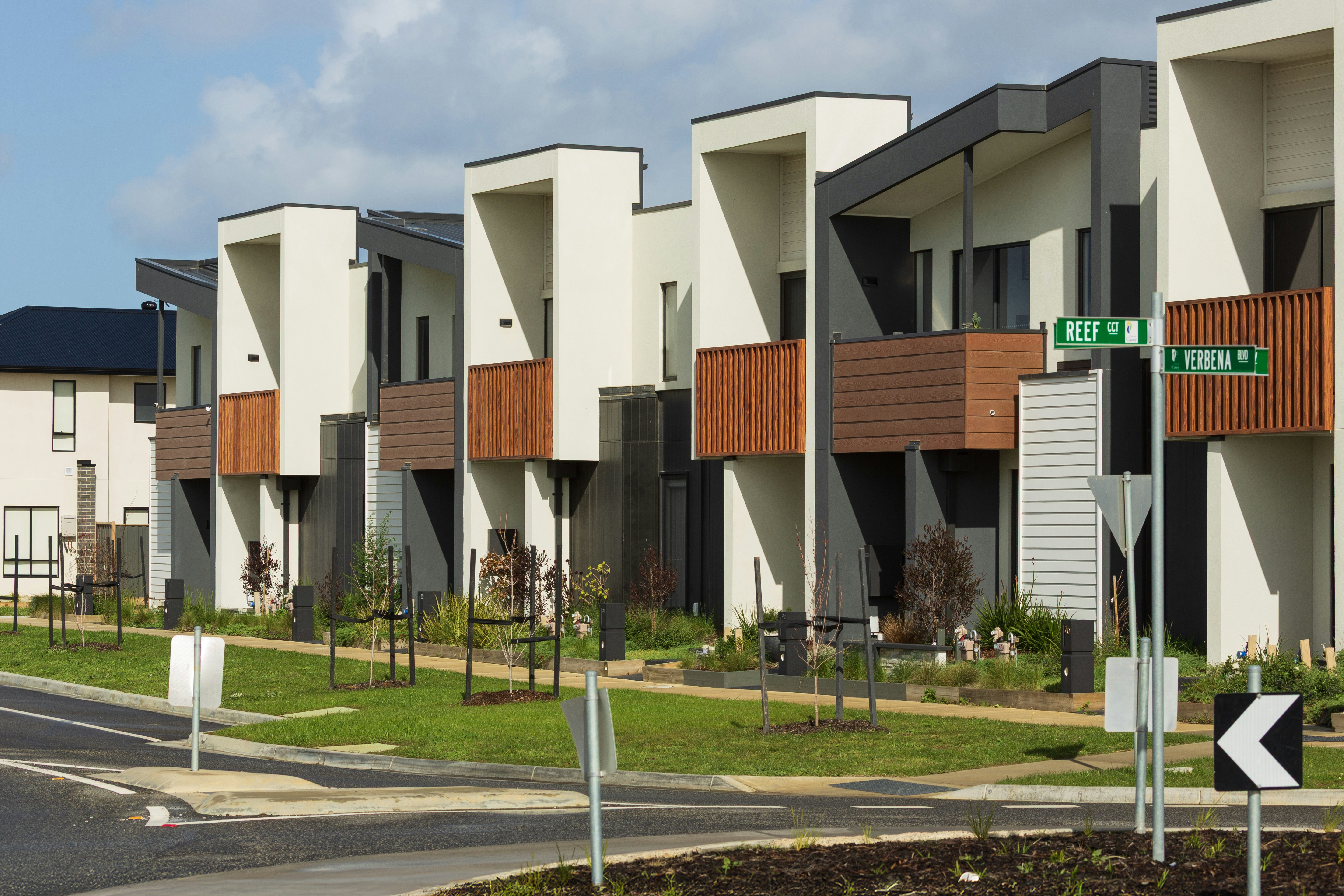 Modern townhouses with geometric designs on a street.