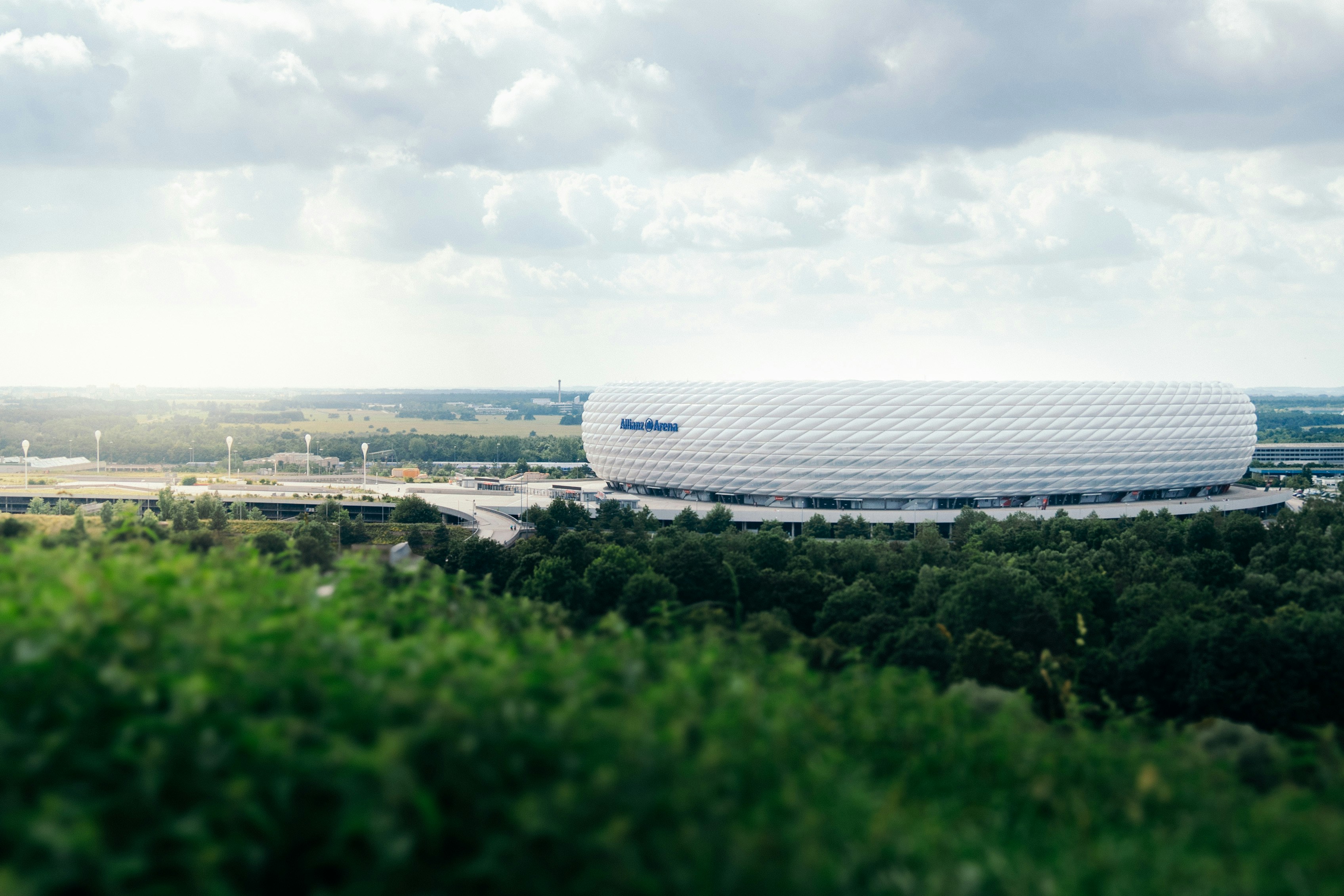 Modern white stadium surrounded by green trees