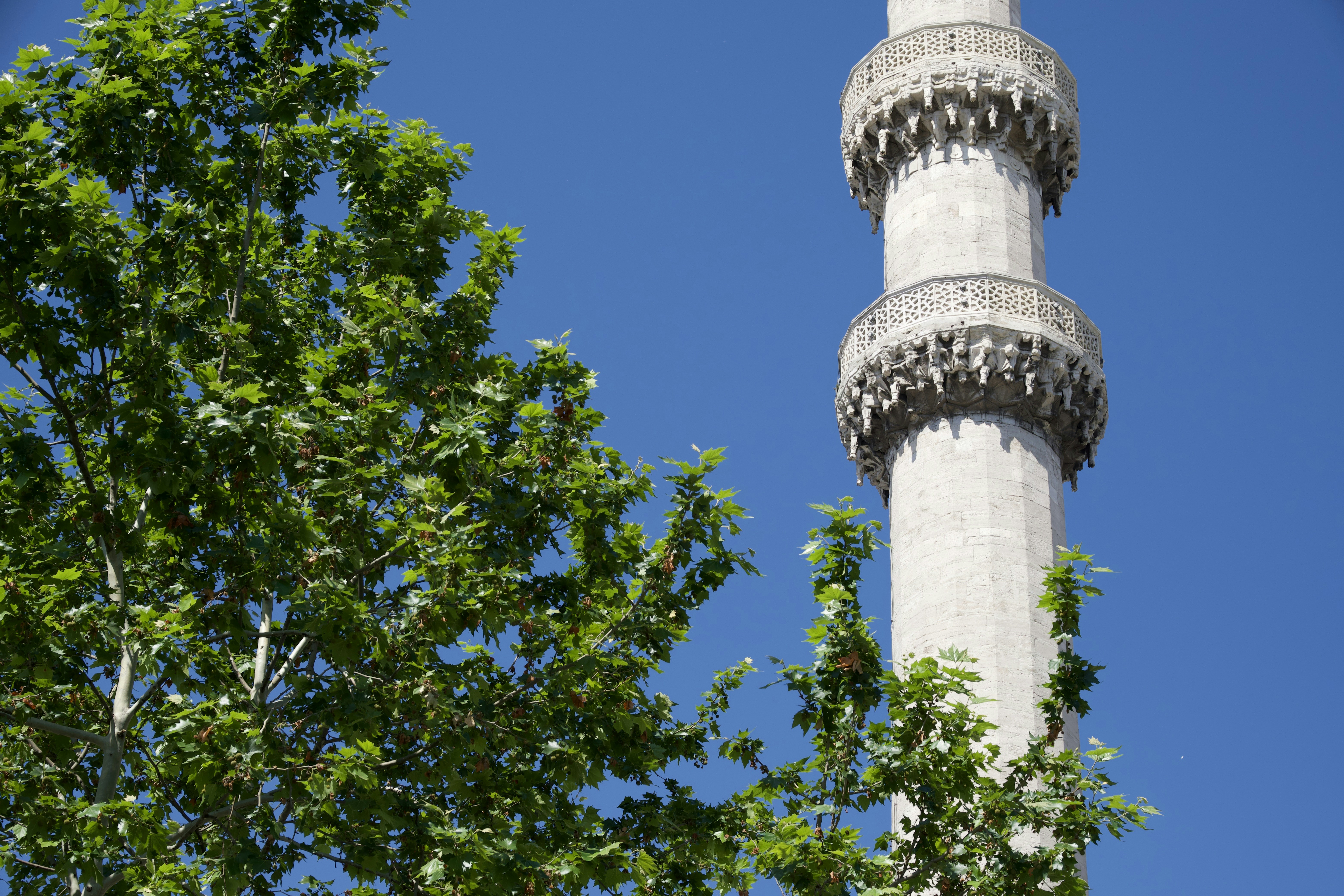 Tall minaret tower against a clear blue sky.