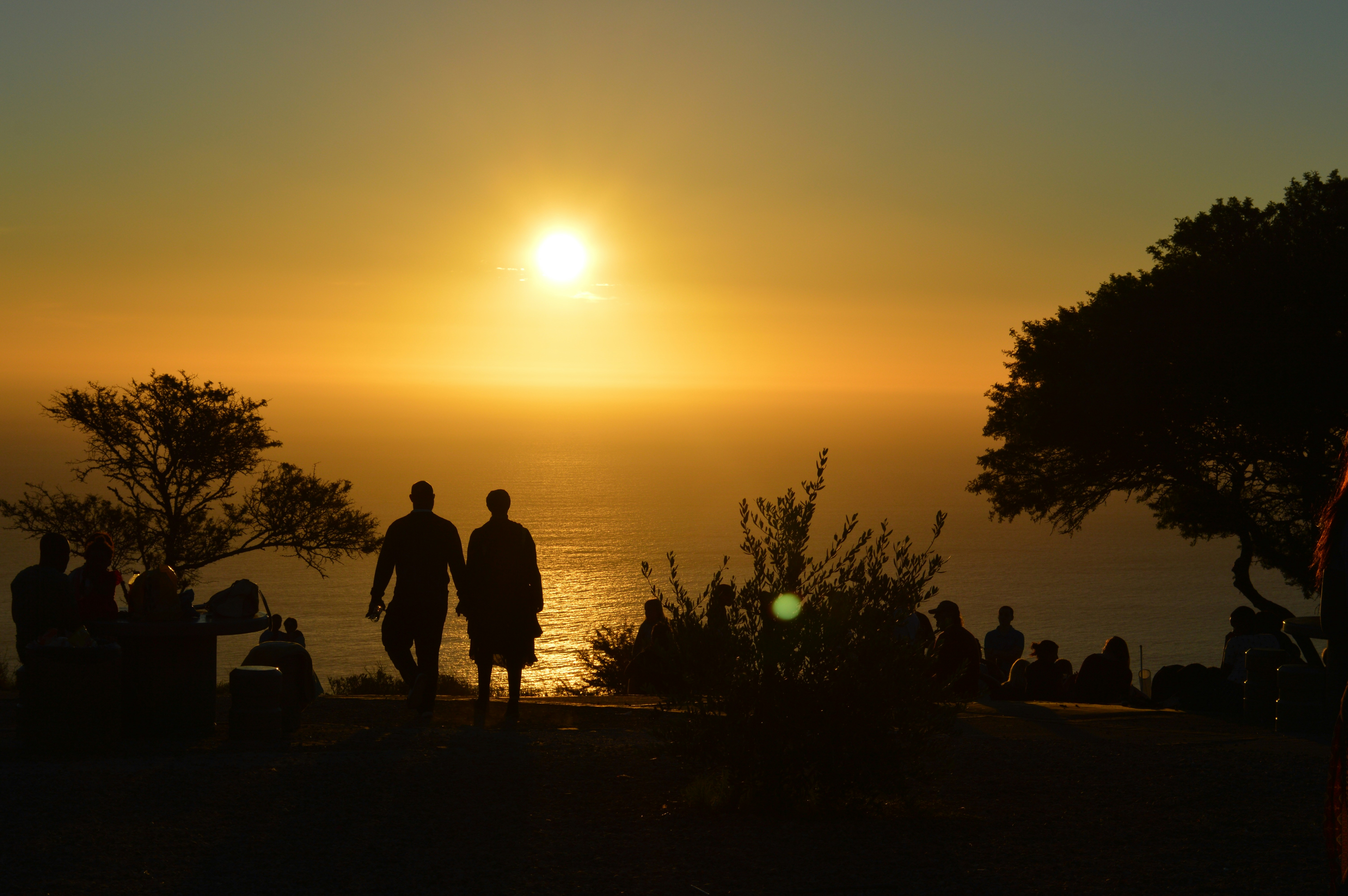 Silhouettes of people watching a vibrant sunset over the ocean.