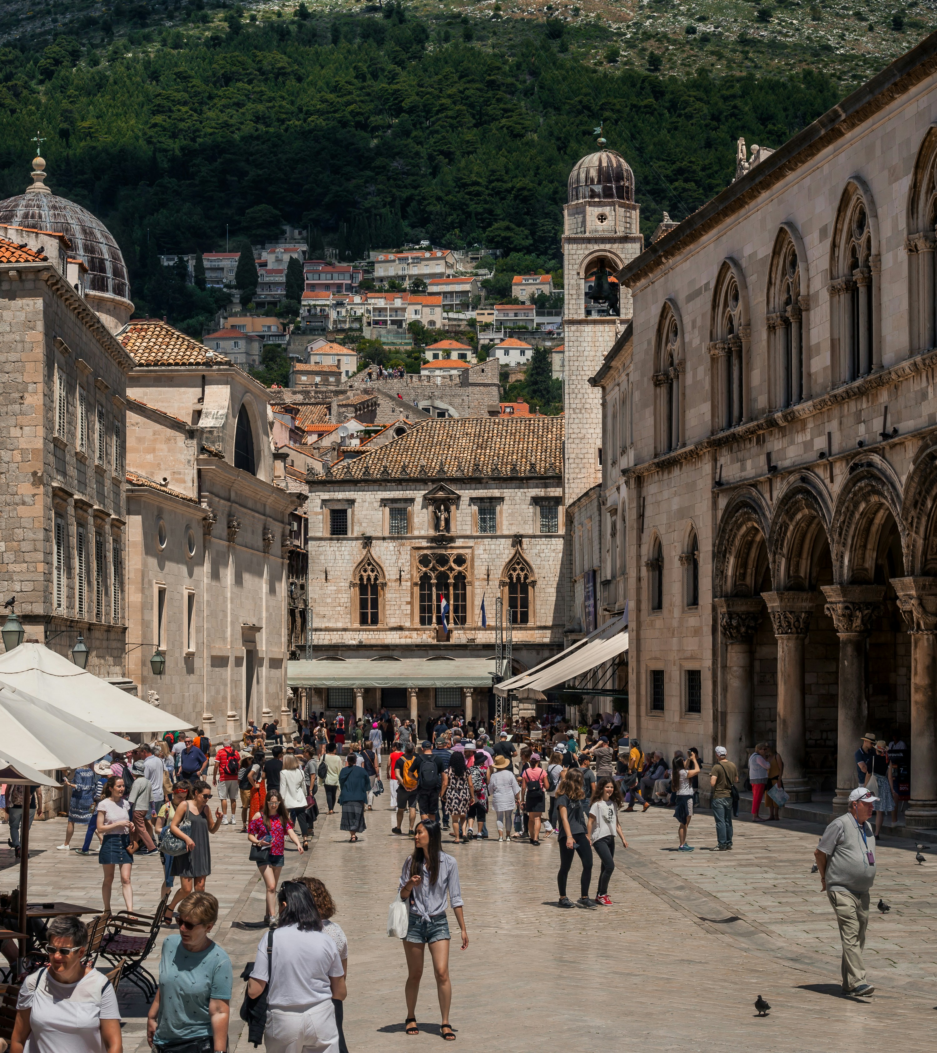Crowded european square with historic buildings and hills.