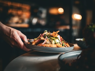 A person serves a plate of gourmet food