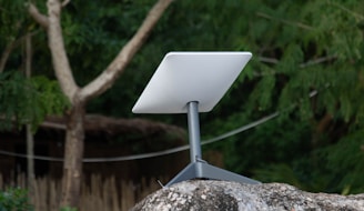 White satellite dish on a stand on rocks.