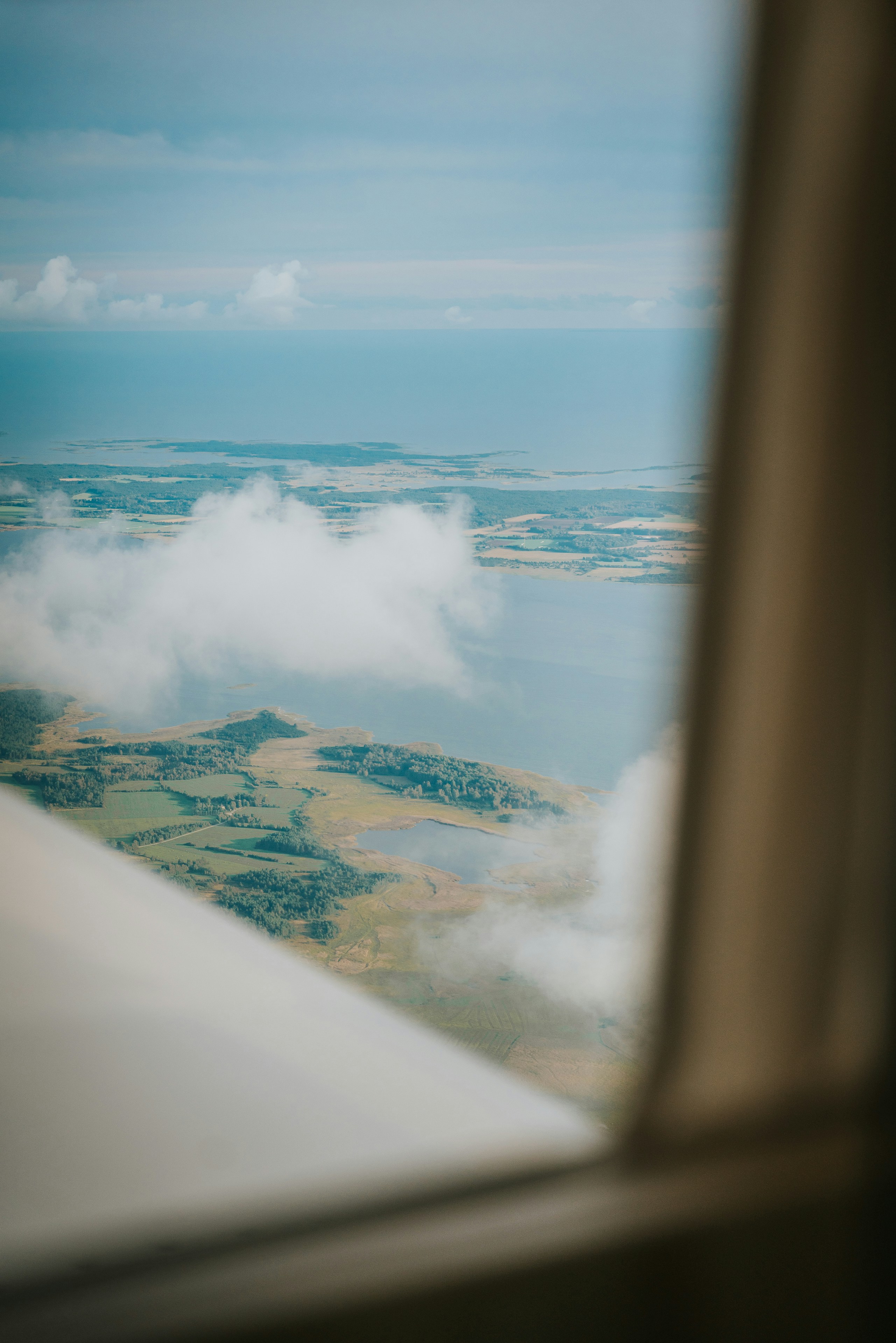 Aerial view of coastal landscape with clouds from airplane window