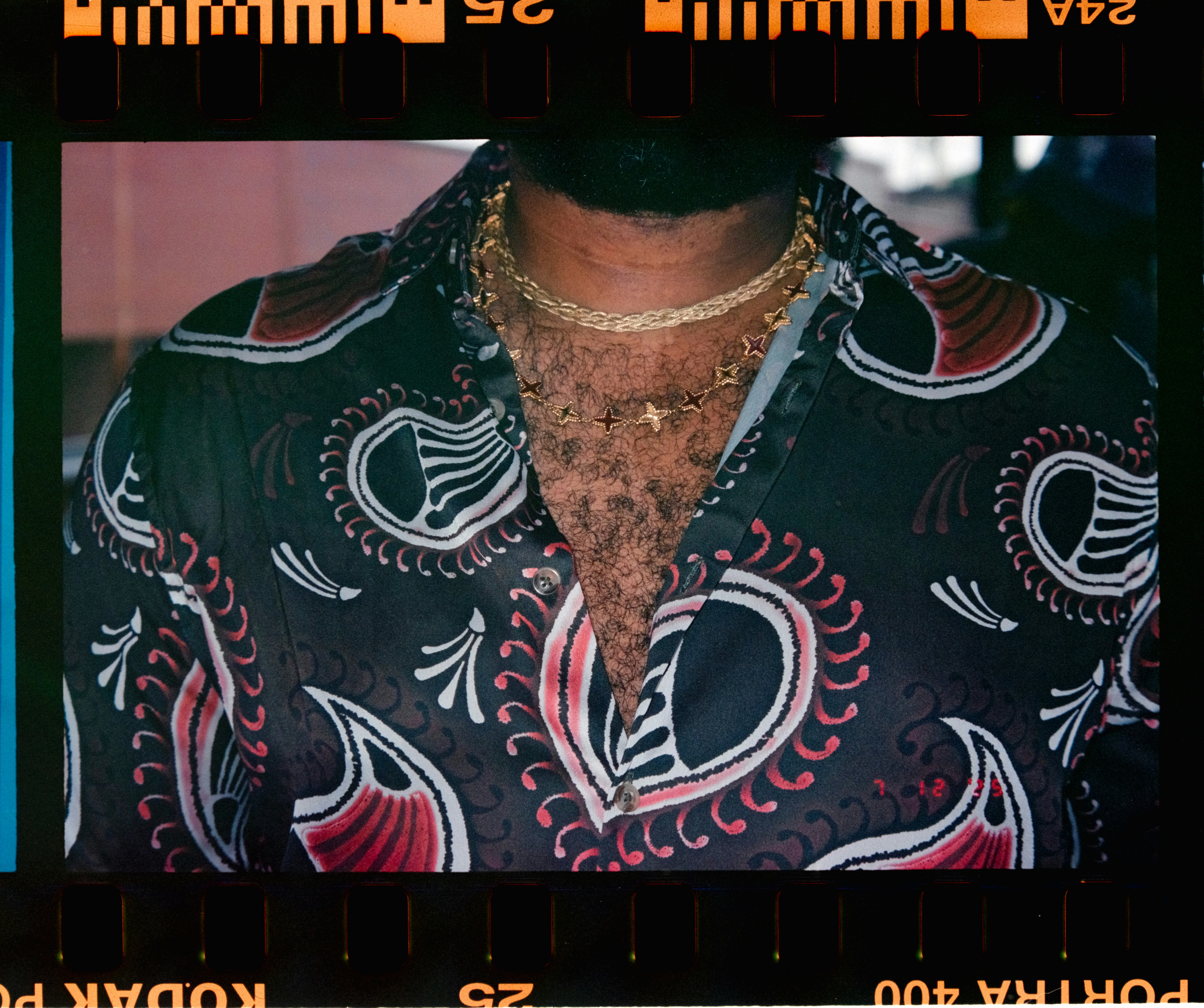 Pria mengenakan kemeja bermotif dan kalung emas