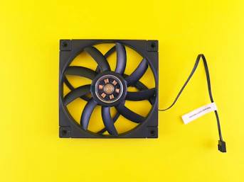 Black computer fan on a bright yellow background