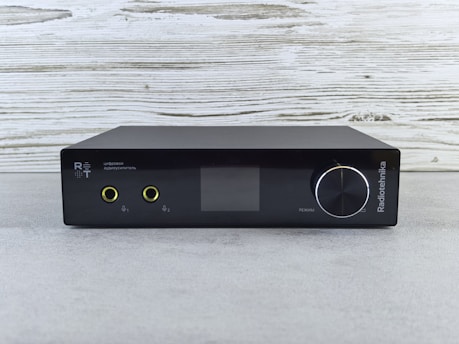 Black audio amplifier with digital display and knobs.