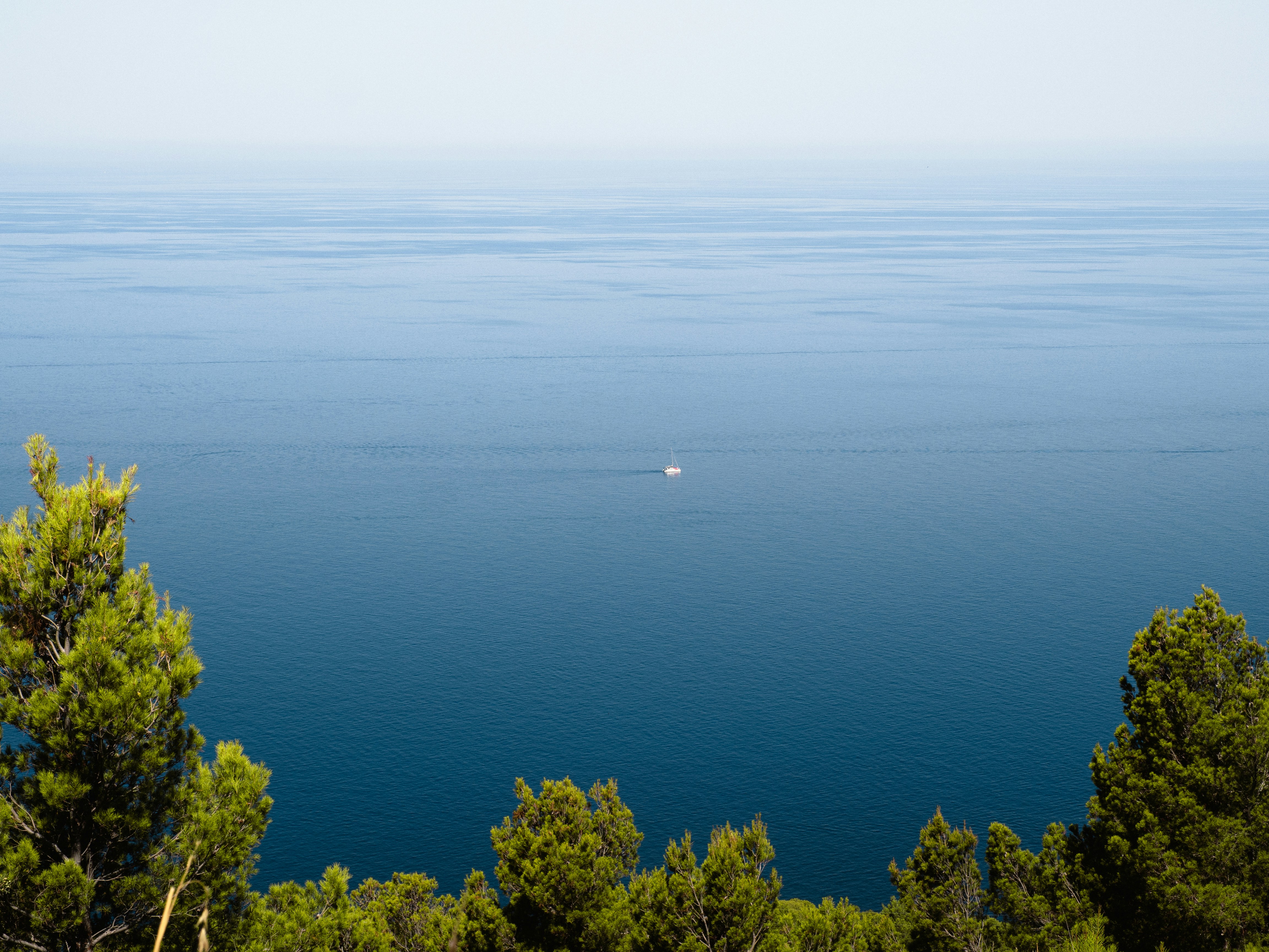 Small boat sailing on a vast blue ocean.