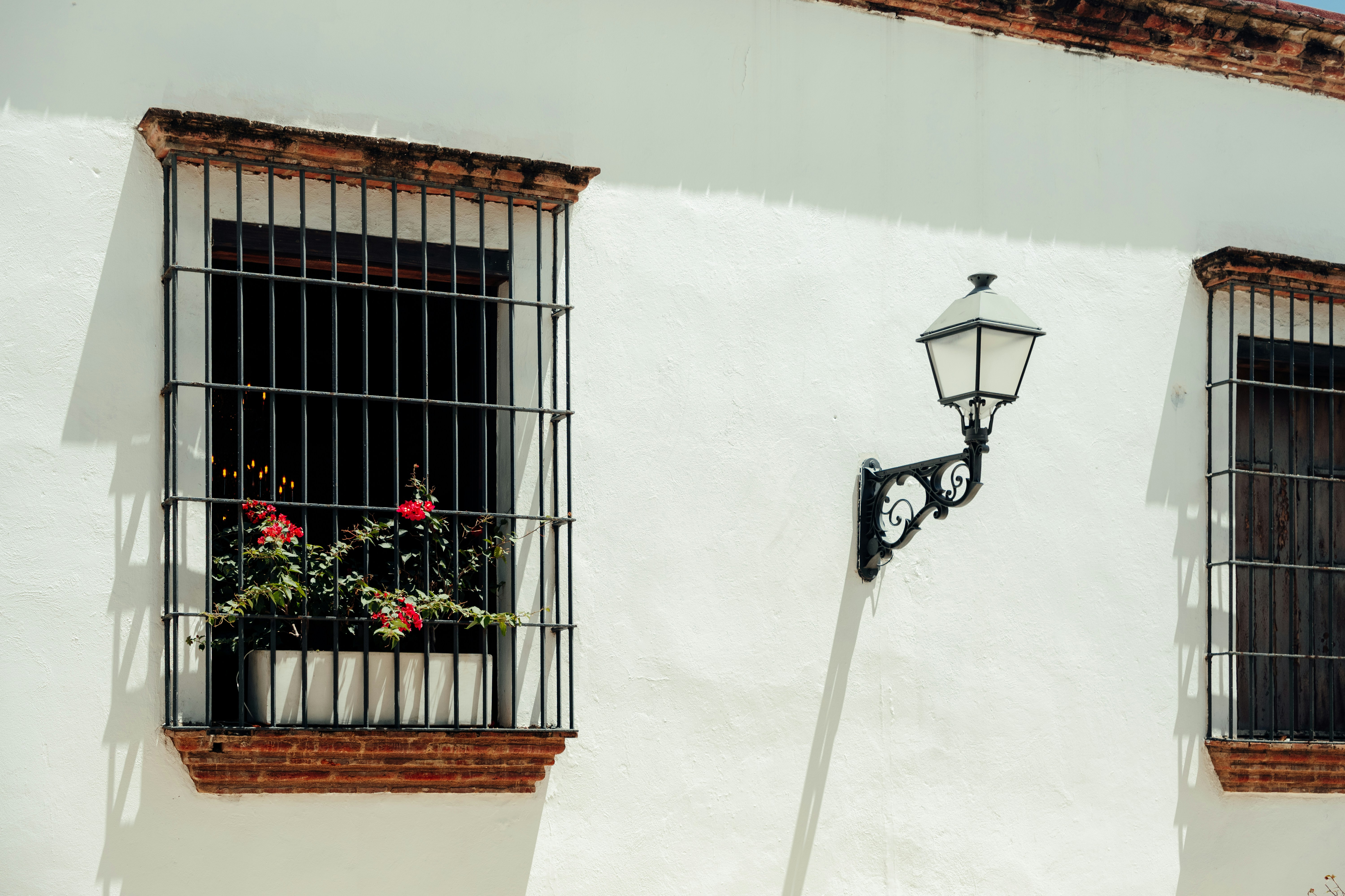 White building facade with barred windows and lamp.