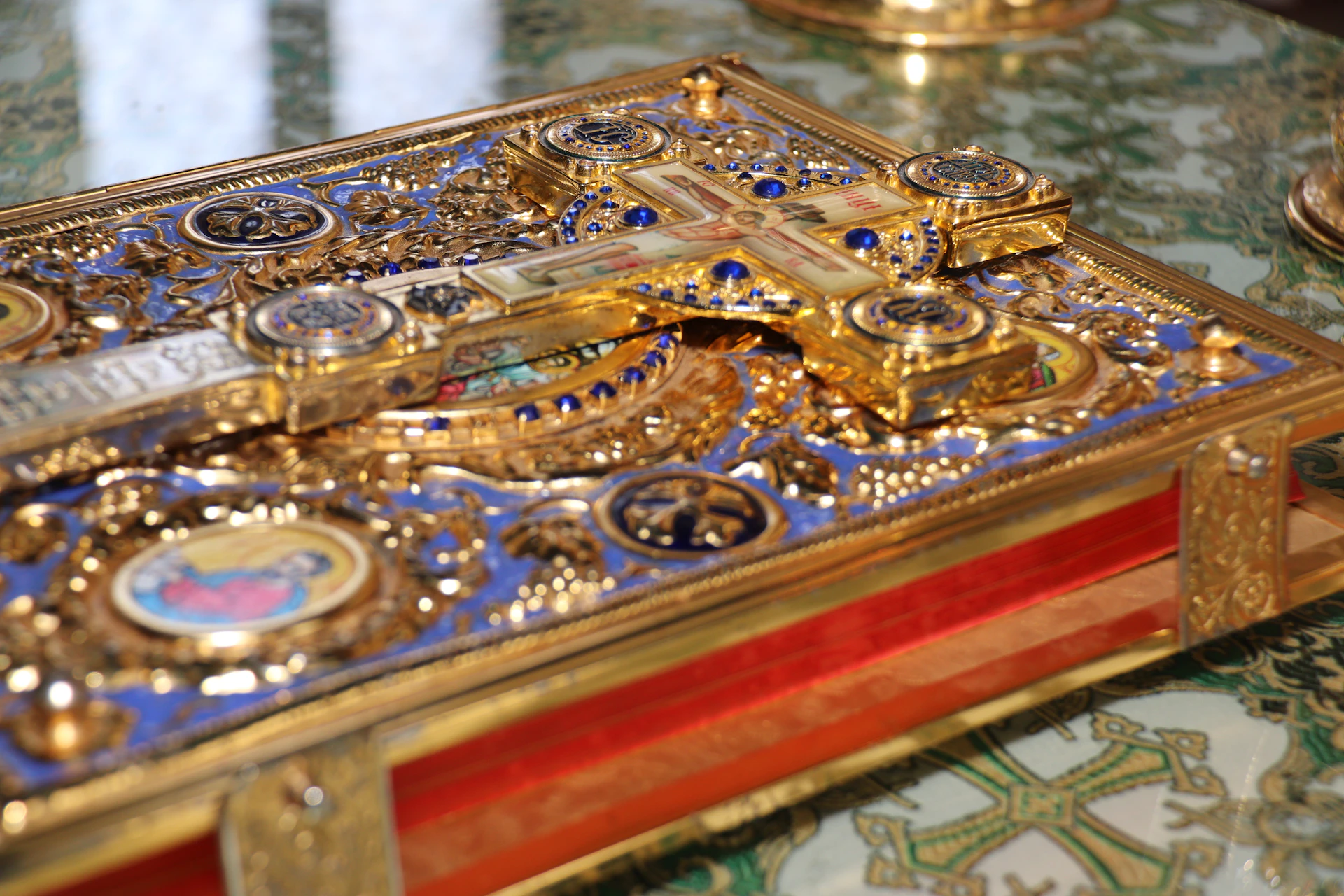 Ornate golden religious book with cross and blue enamel details