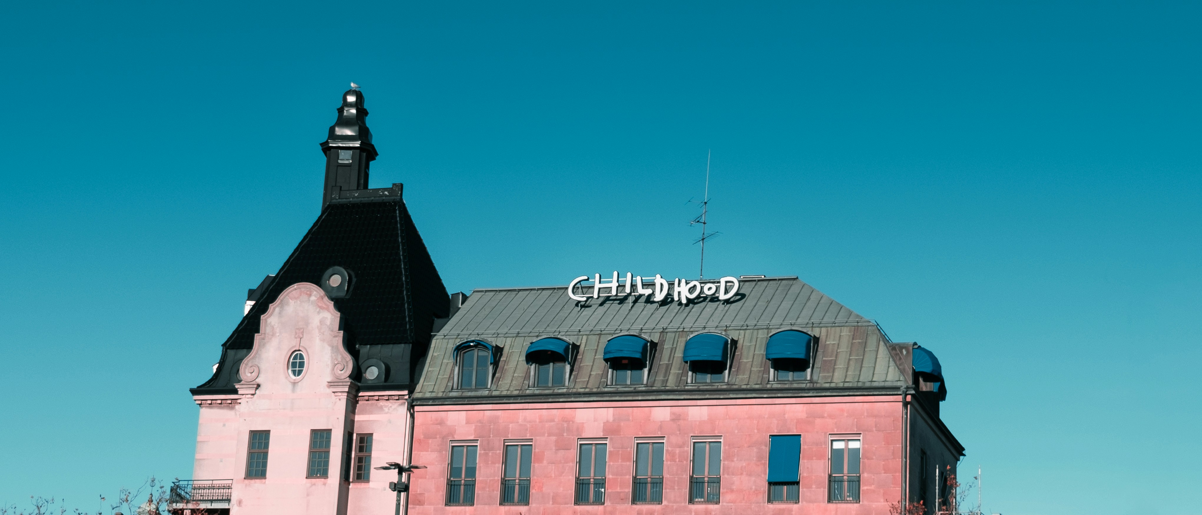 Rosafarbenes Gebäude mit dunklem Dach und Turm