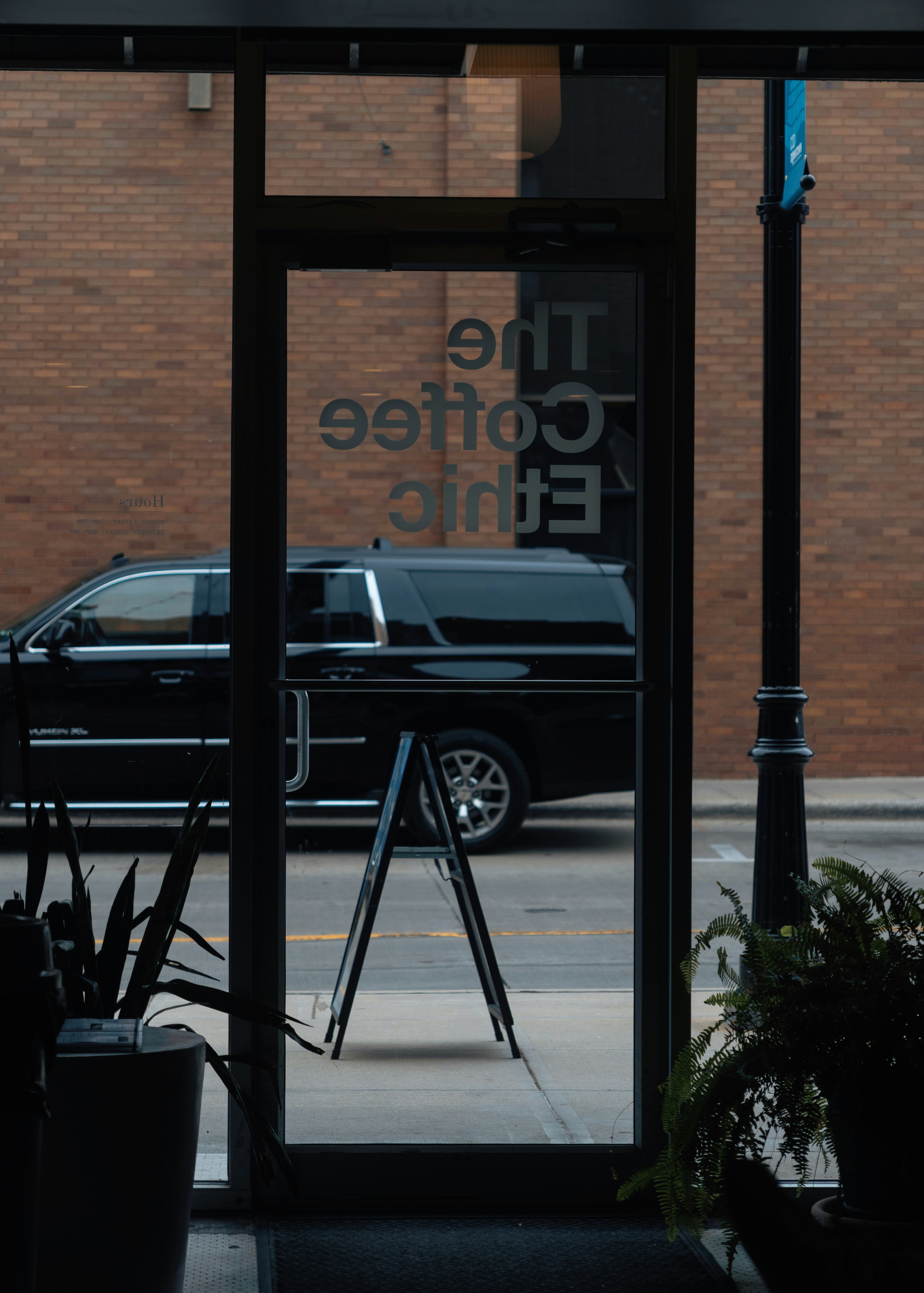 Black suv parked outside a coffee shop entrance.