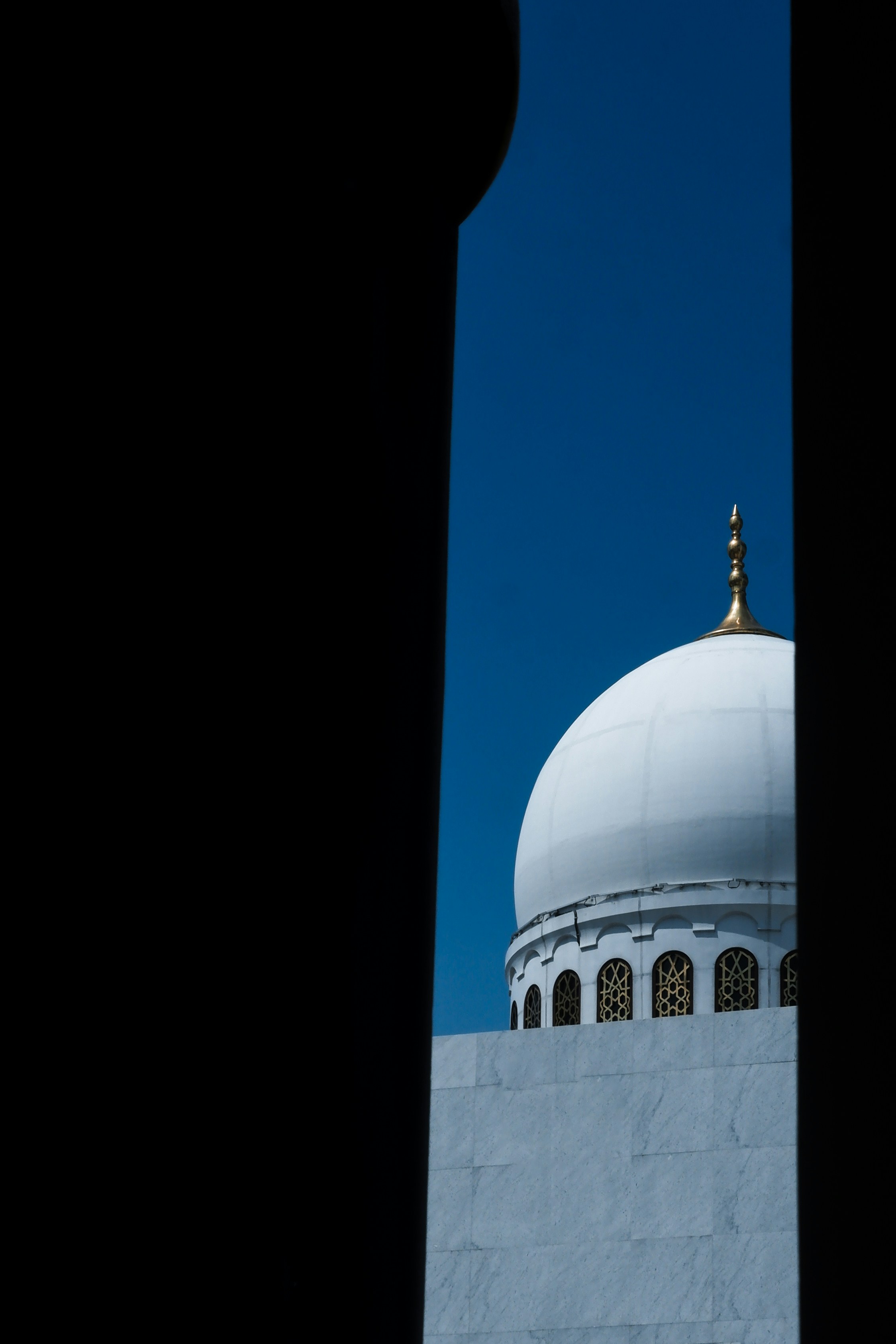 White mosque dome against a clear blue sky.