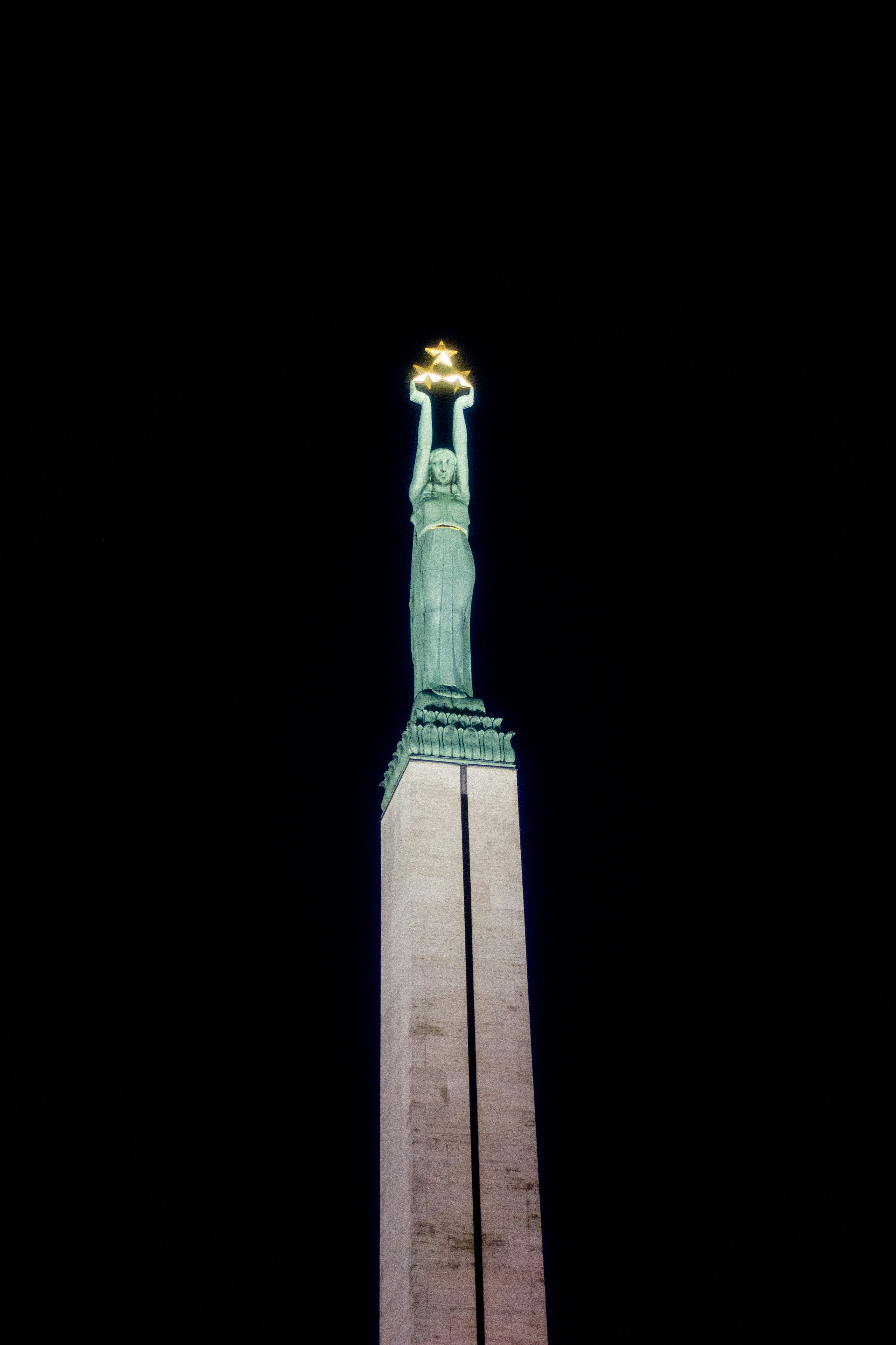 Statue holding a golden star against dark sky