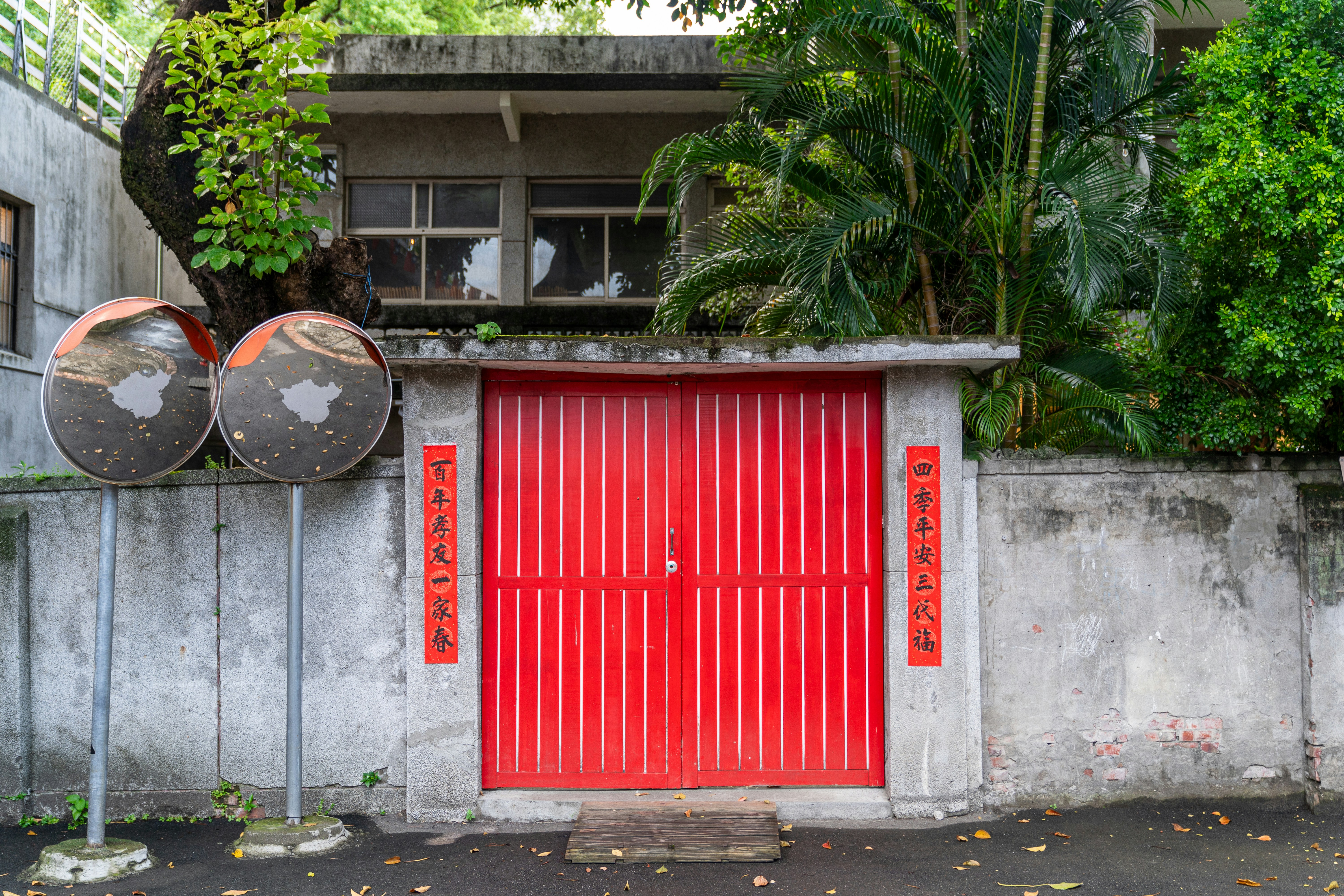 Rote Tore mit chinesischen Couplets auf Betonwand.