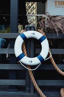 Lifebuoy with rope hangs on a wooden fence.