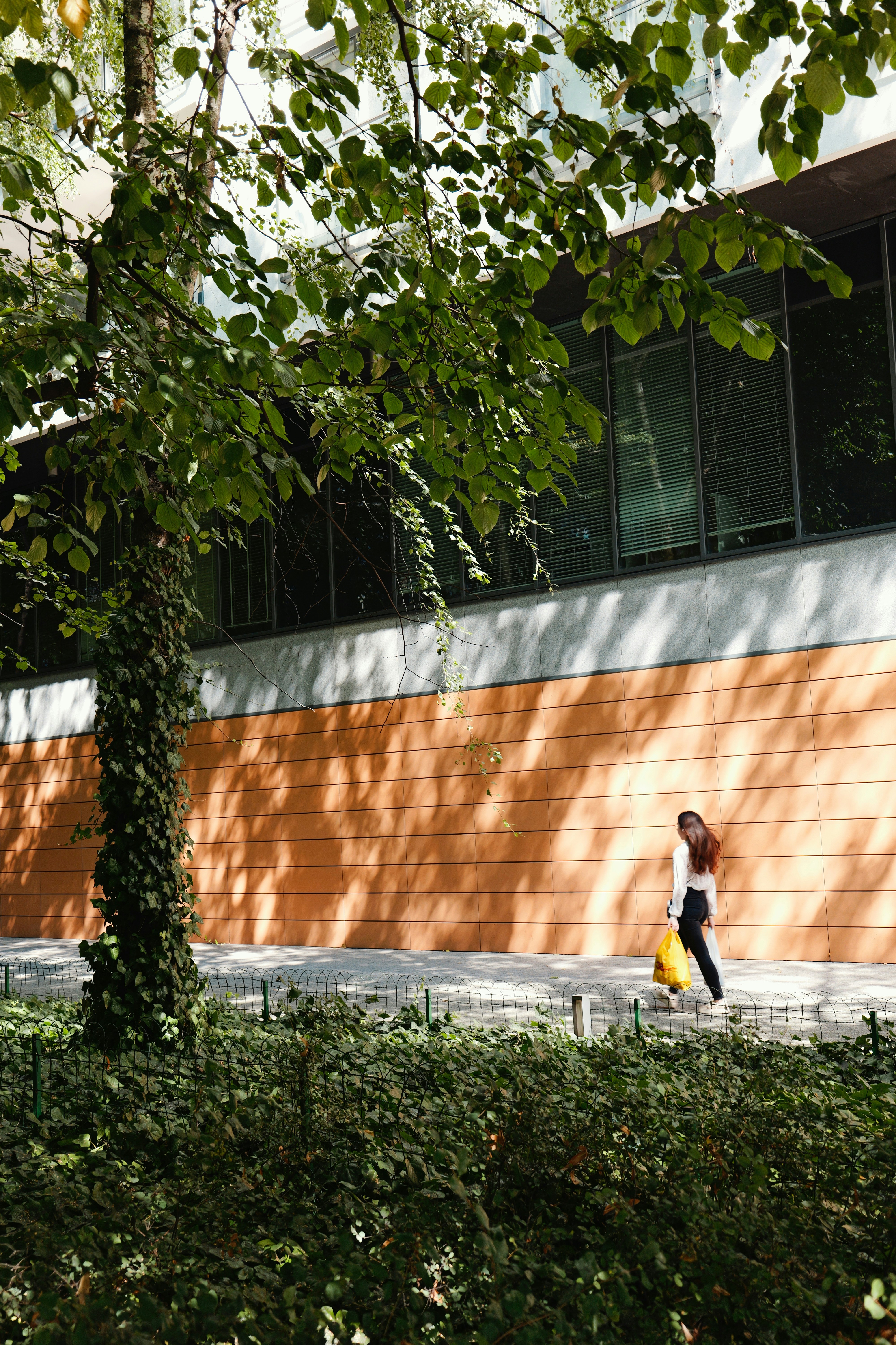 Femme passant devant un bâtiment au mur orange.