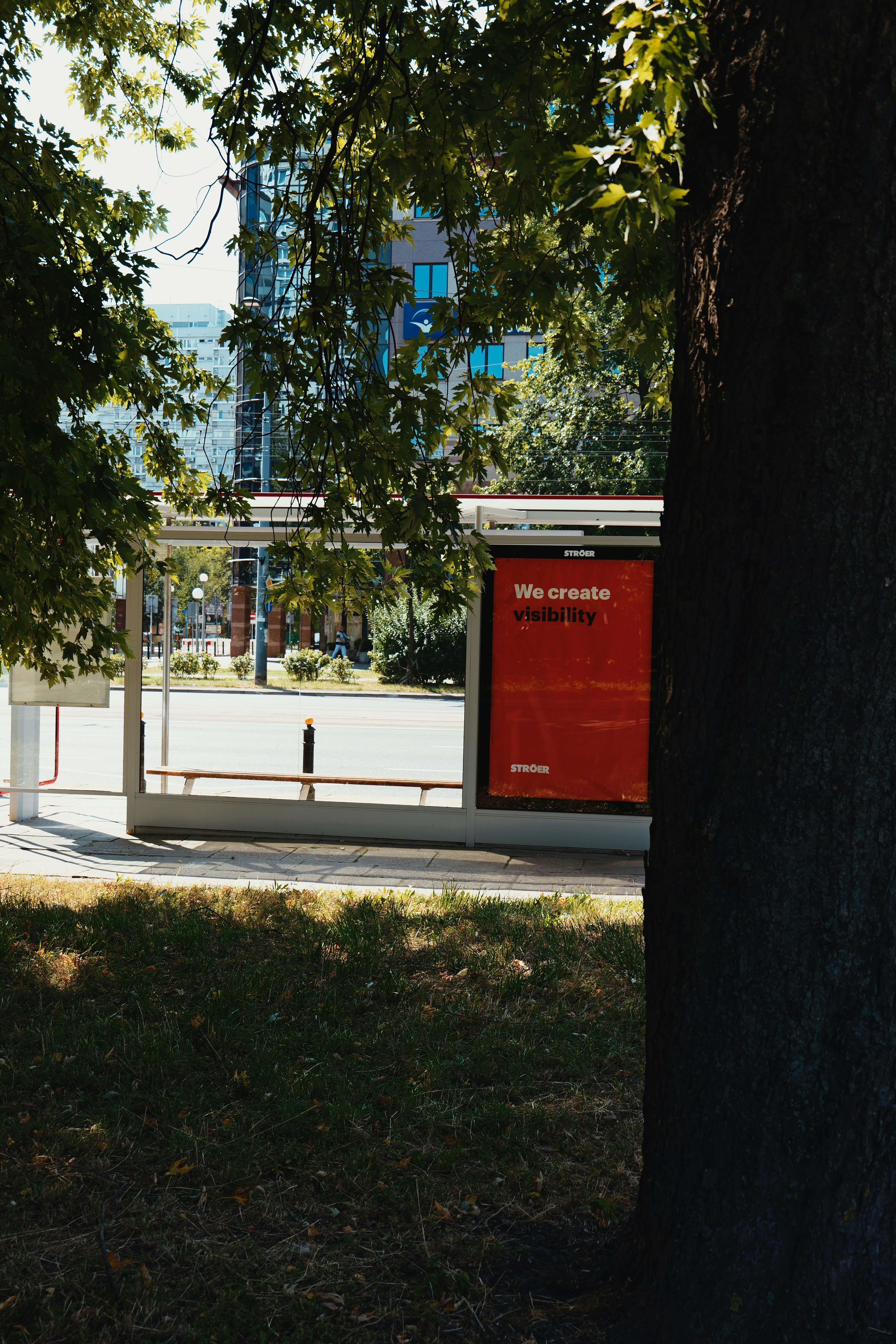 Arrêt de bus avec publicité rouge derrière l’arbre