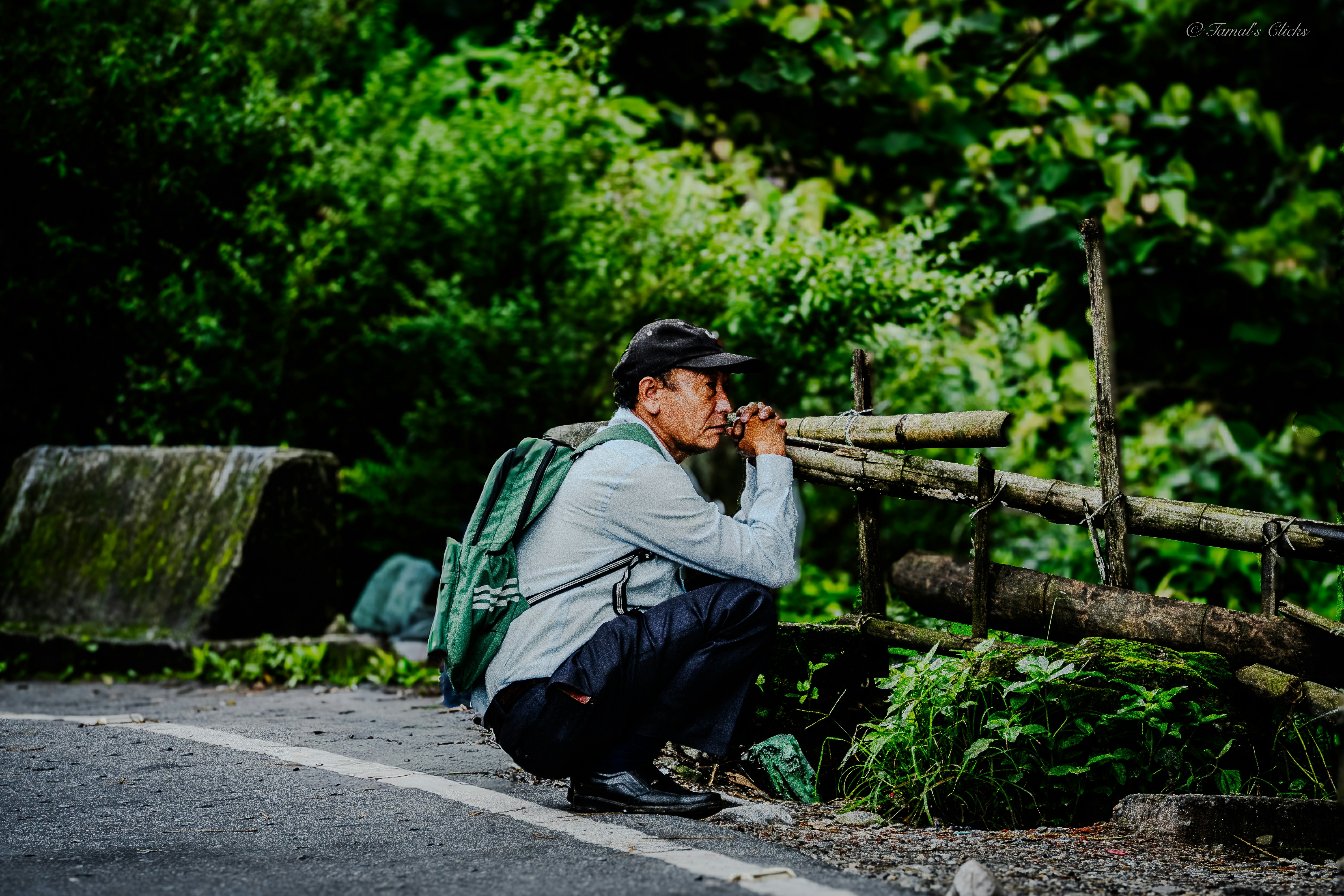 Man with backpack crouching and looking through binoculars