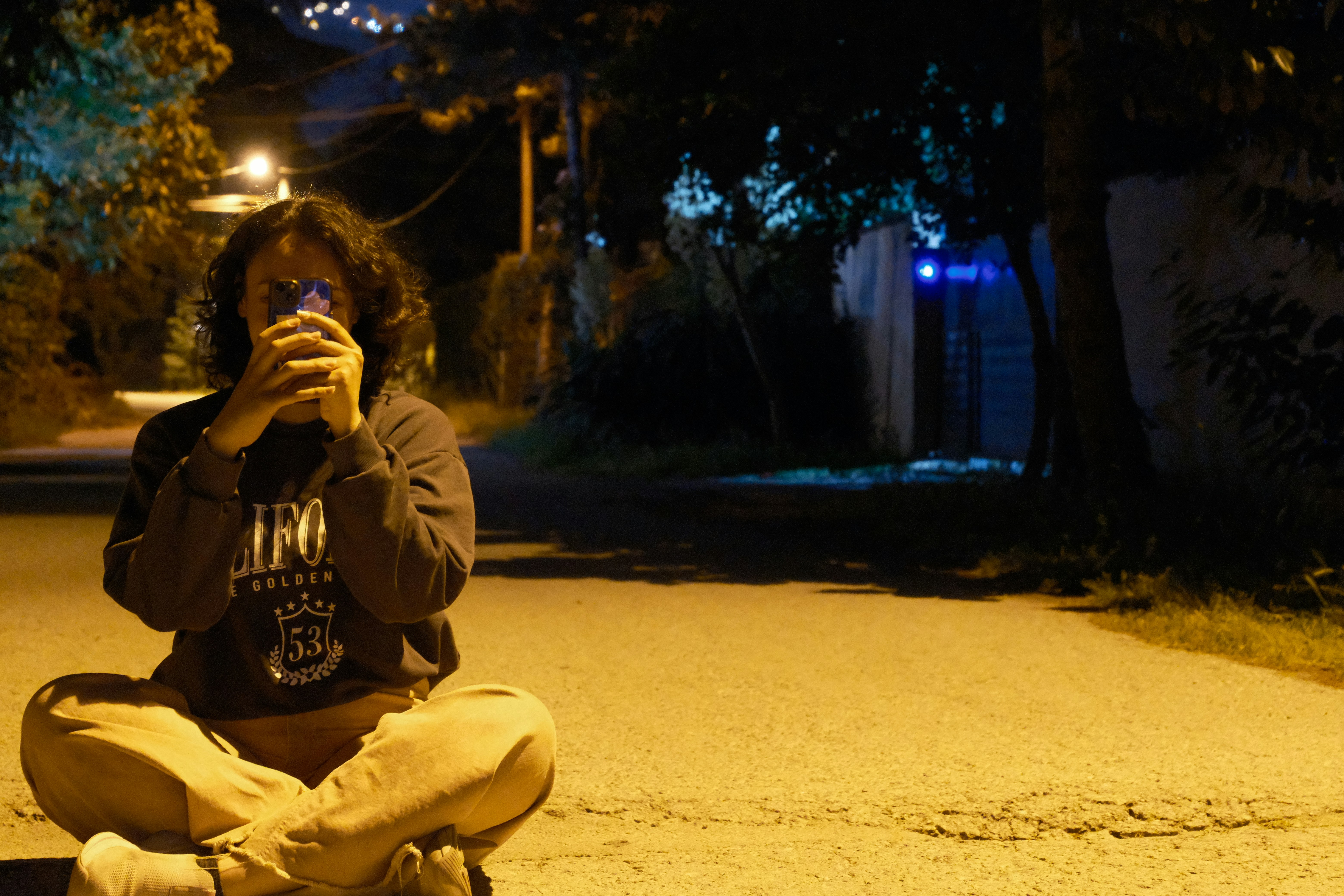 Person sitting on street at night drinking