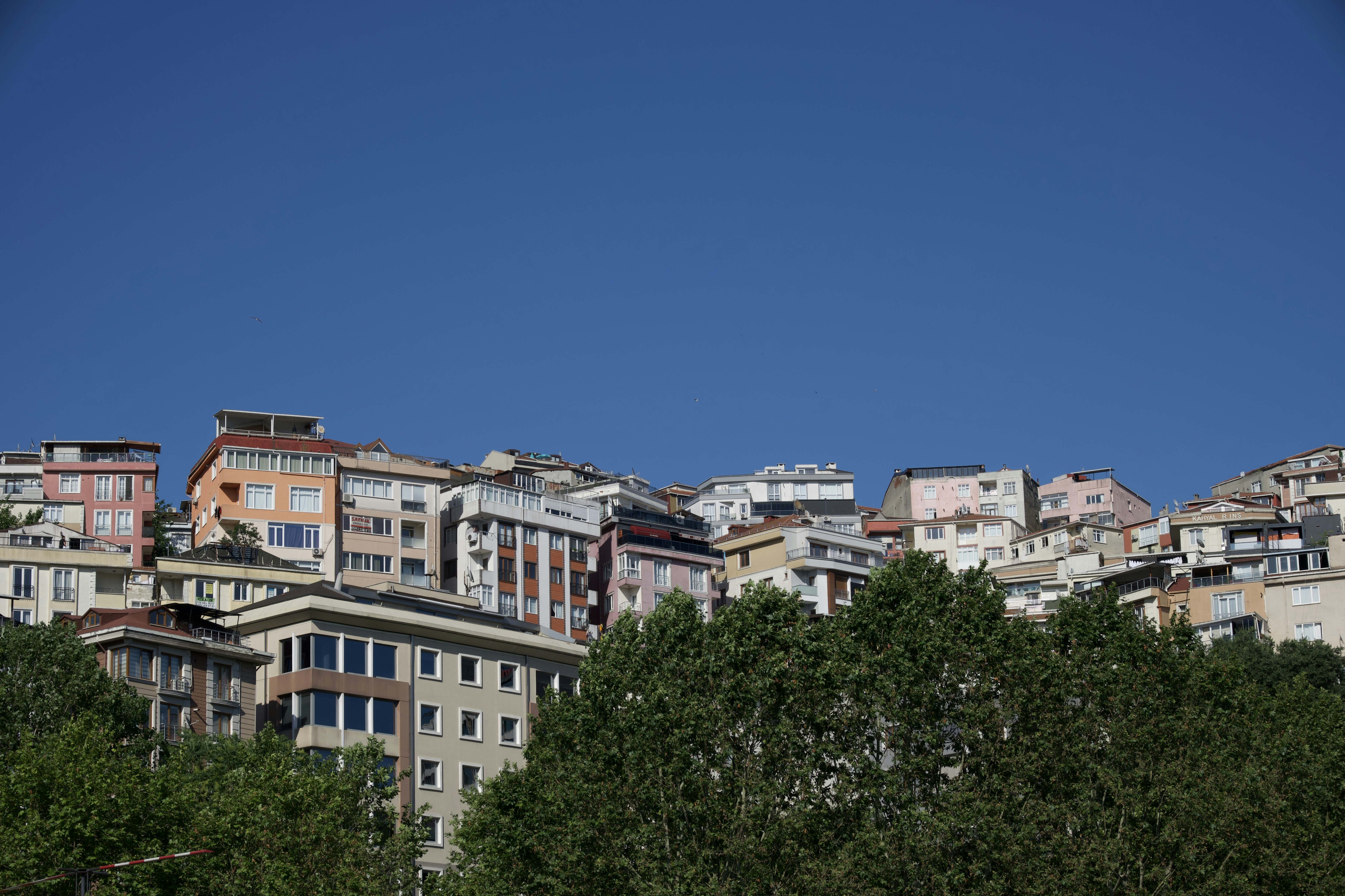 City buildings on a hill under a clear blue sky.