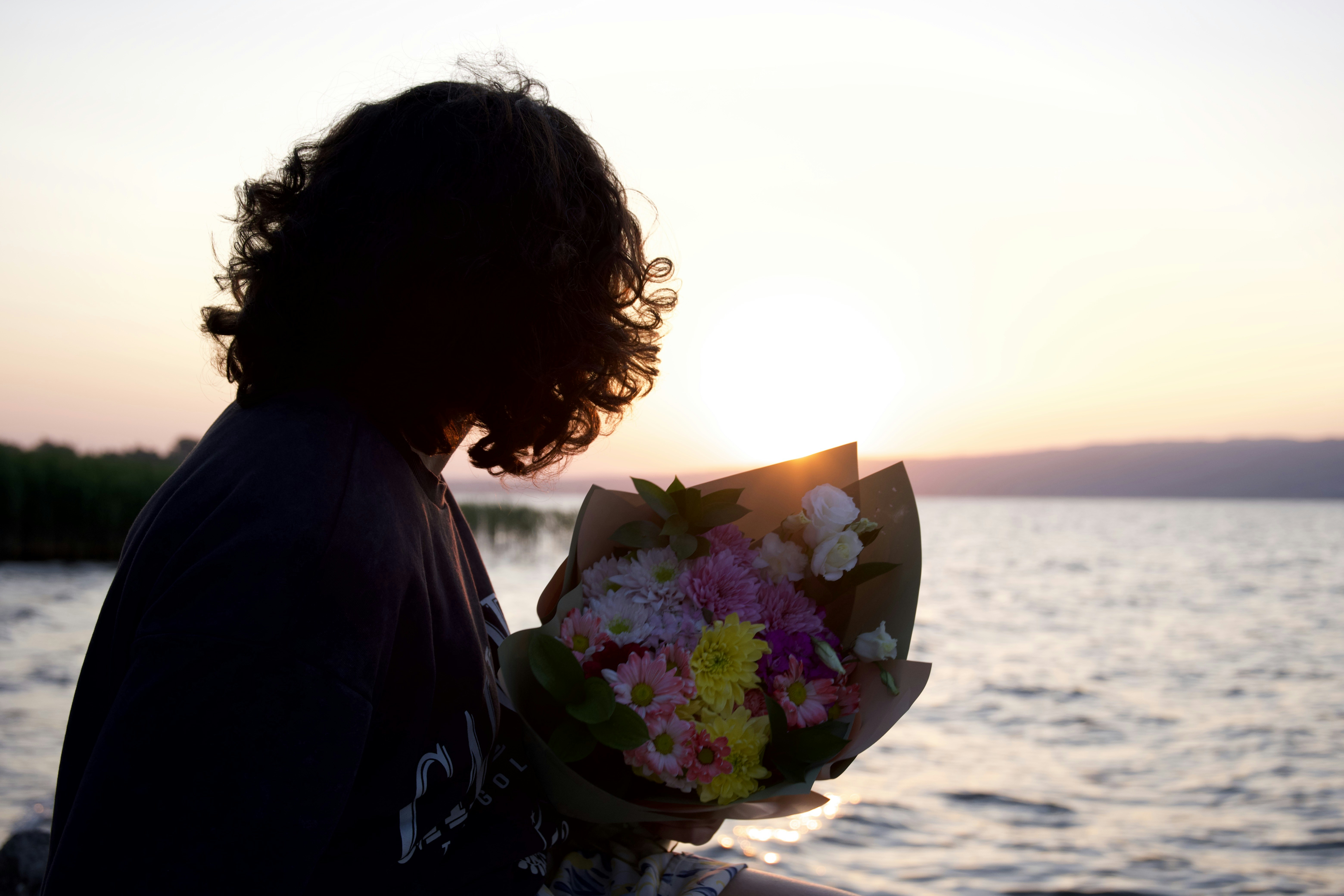 Person holding a bouquet of flowers at sunset