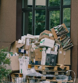 Cardboard boxes and paper waste piled on wooden pallets.
