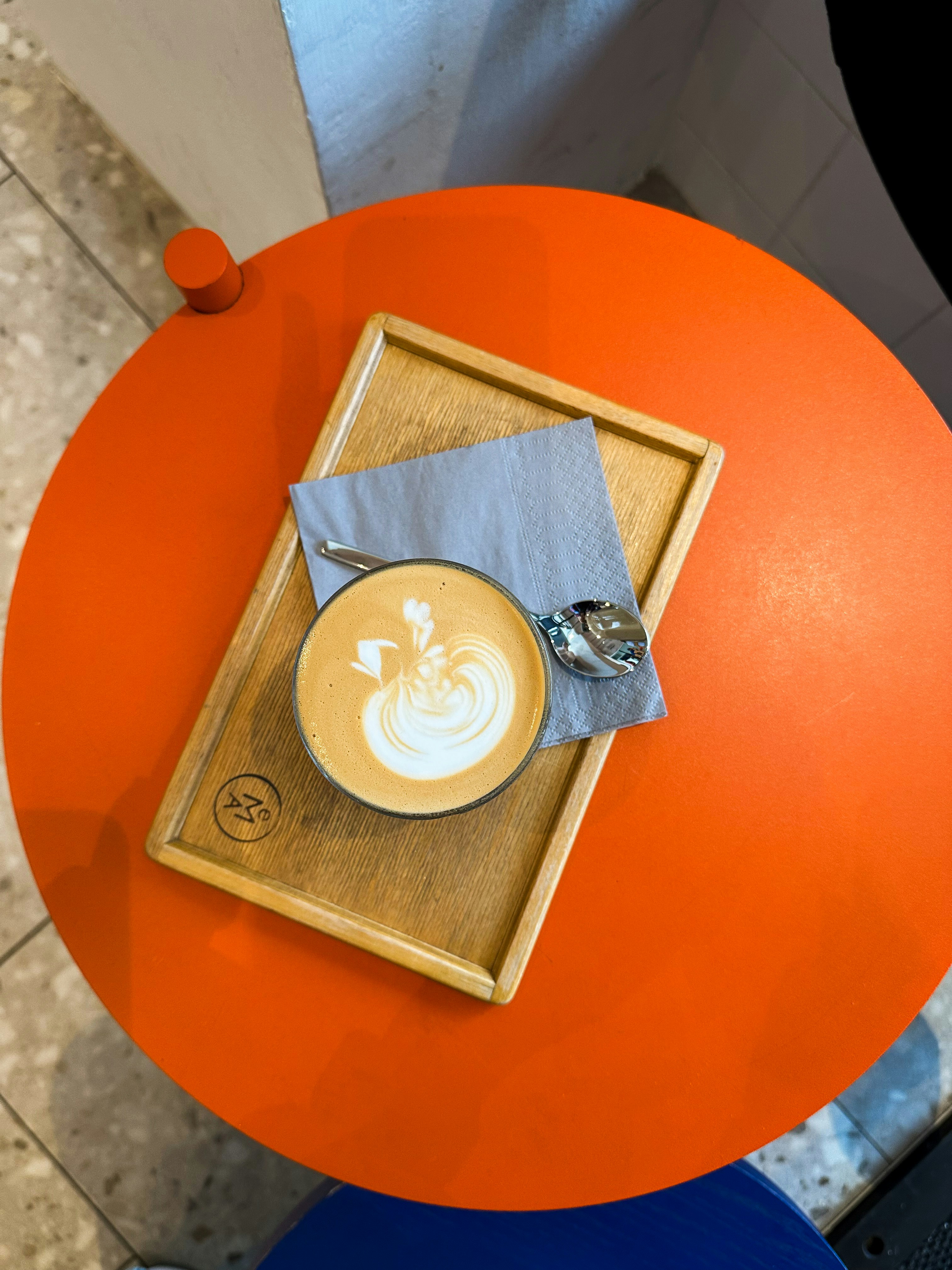 Tasse Latte mit Kunst auf orangefarbenem Tisch