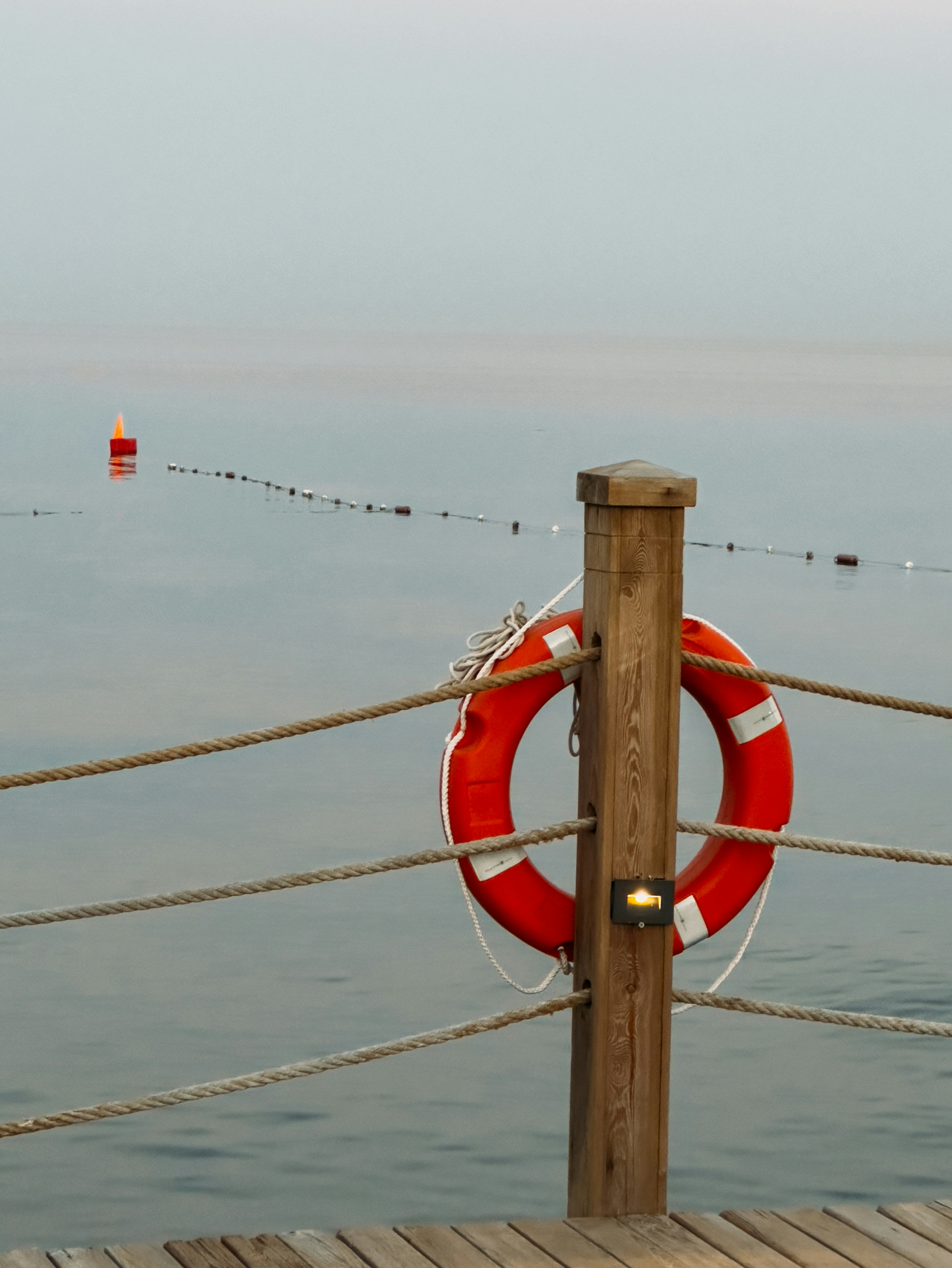 Roter Rettungsring, der bei ruhigem Wasser an Holzpfosten befestigt ist