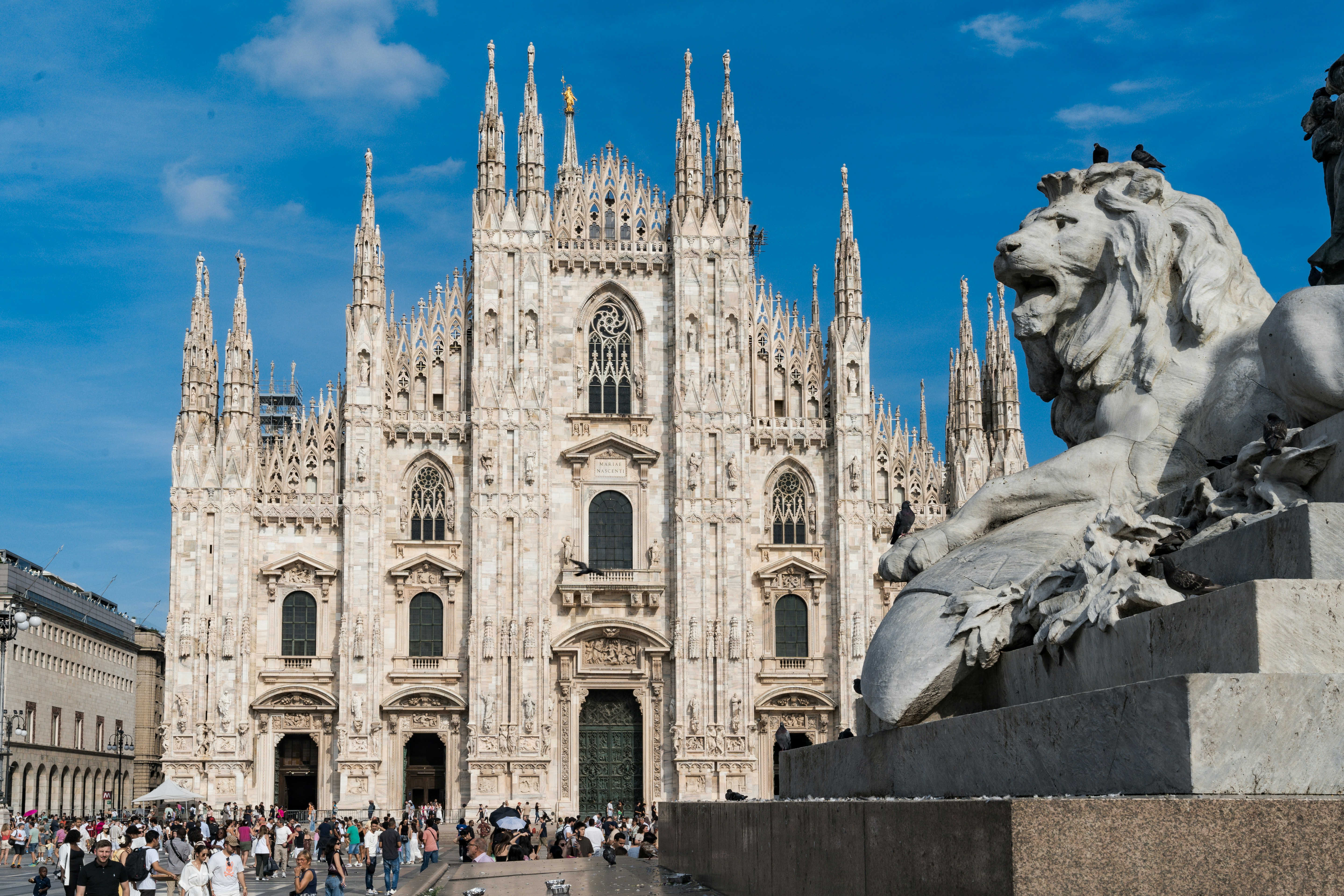 Milan cathedral with a lion statue in foreground